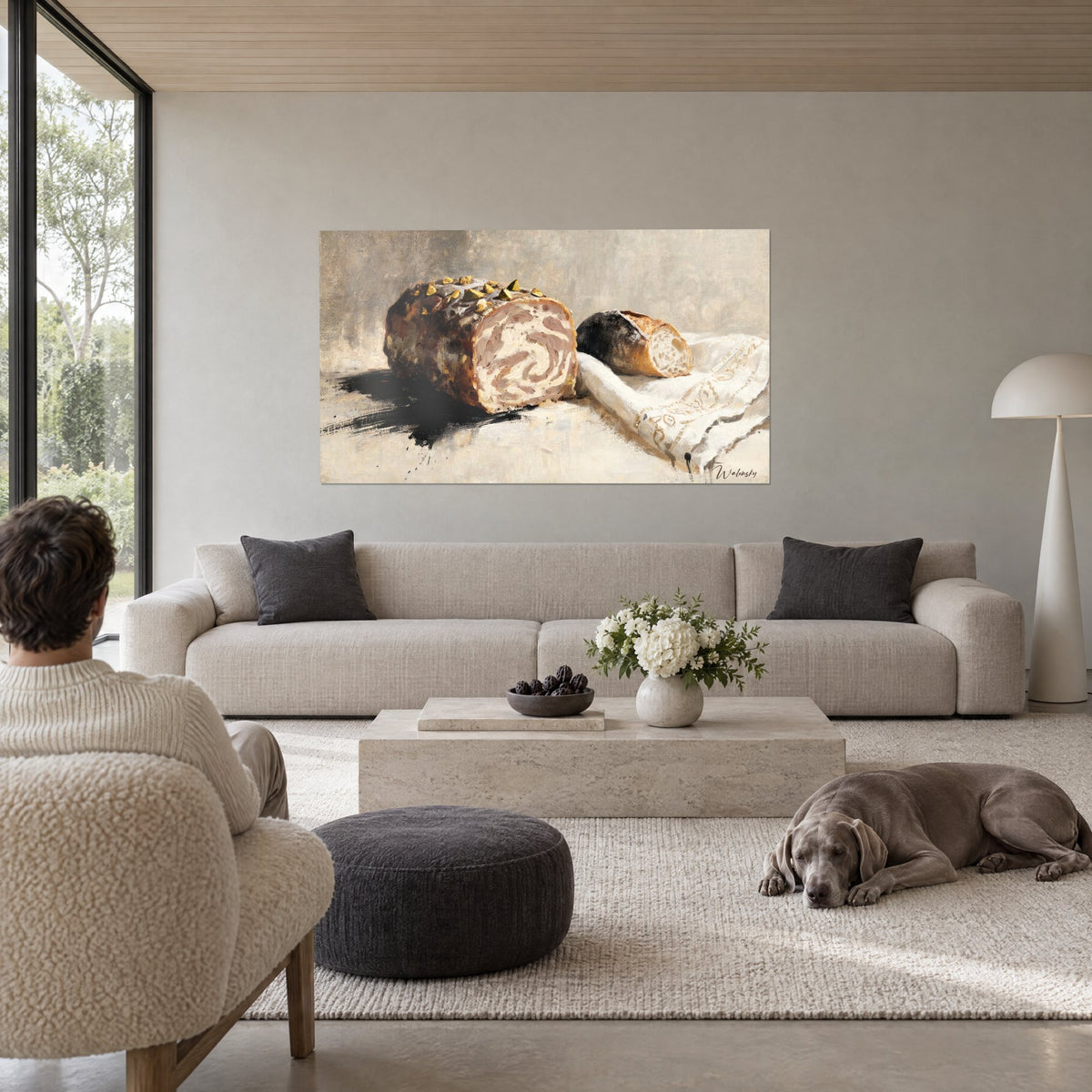 Tableau galantine marbrée crème et bronze piquée de pistaches vertes, linge brodé blanc, au-dessus d'un canapé dans un salon lumineux