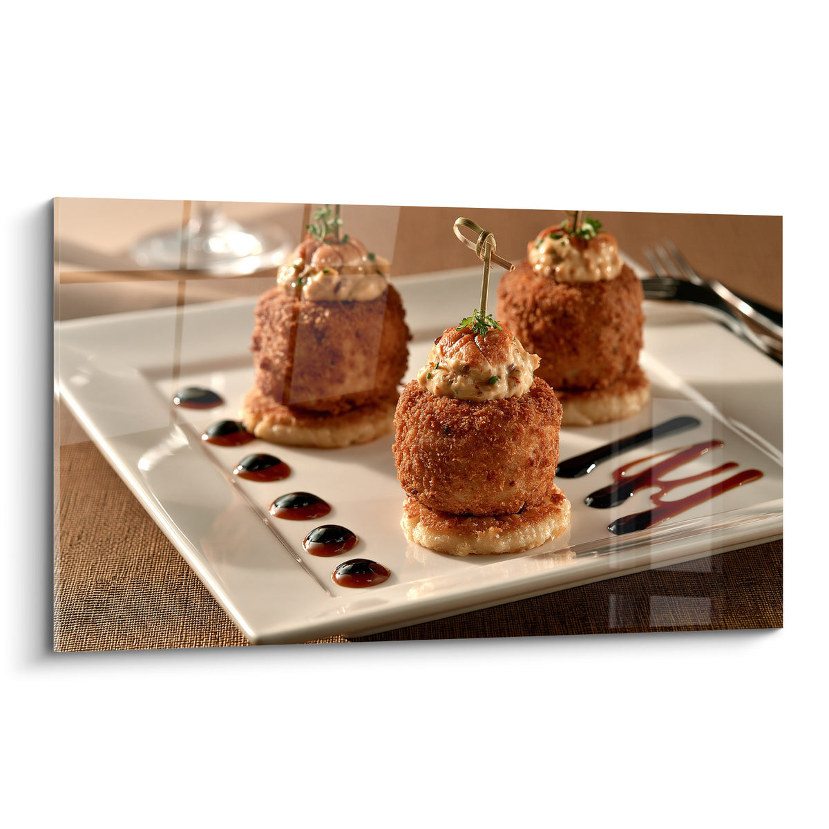 Trois croquettes dorées et blanches garnies de crème sur assiette rectangulaire, sauce brune en filets