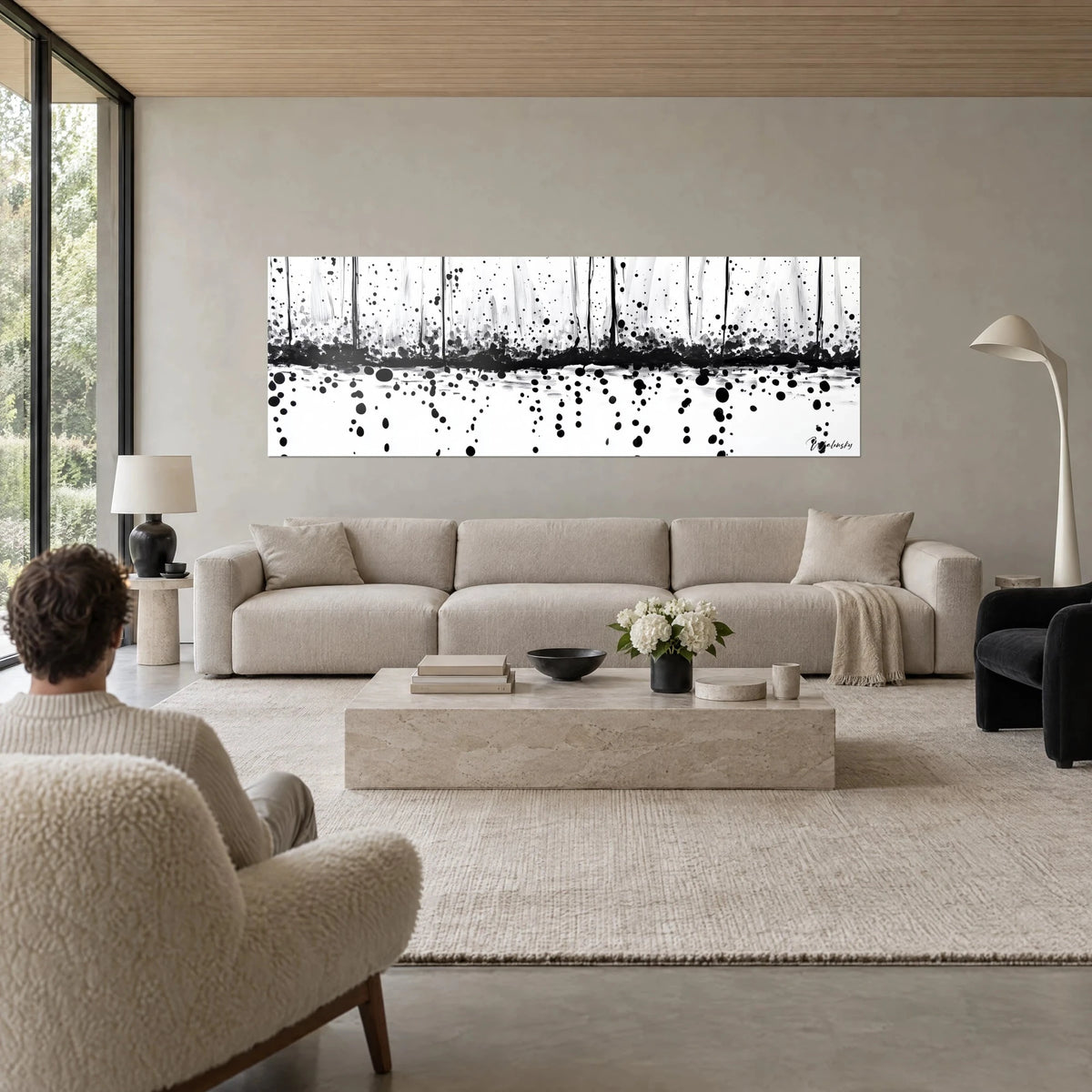 Gemälde mit schwarzen Tintentropfen, die auf weißen Grund fallen, kohlschwarzes Band und senkrechte Striche, über einem Sofa in einem hellen Wohnzimmer
