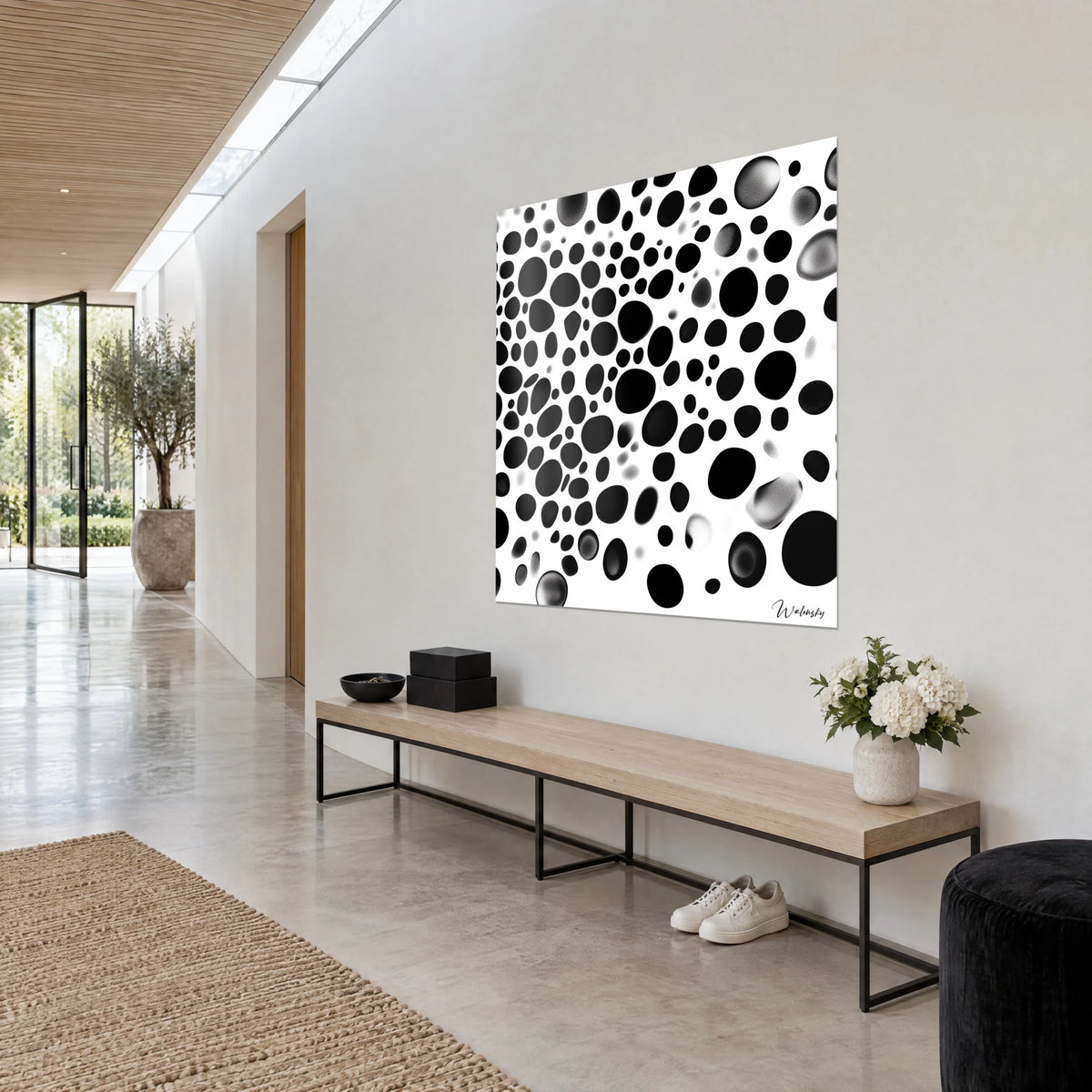Wall art with matte black and grey gradient oval pebbles on bright white, perspective view on the wall of a light hallway