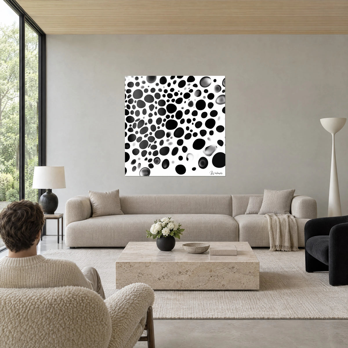 Gemälde mit runden schwarzen und rauchgrauen Tintenklecksen auf weißem Hintergrund, punktierte Körnung, über einem Sofa in einem hellen Wohnzimmer