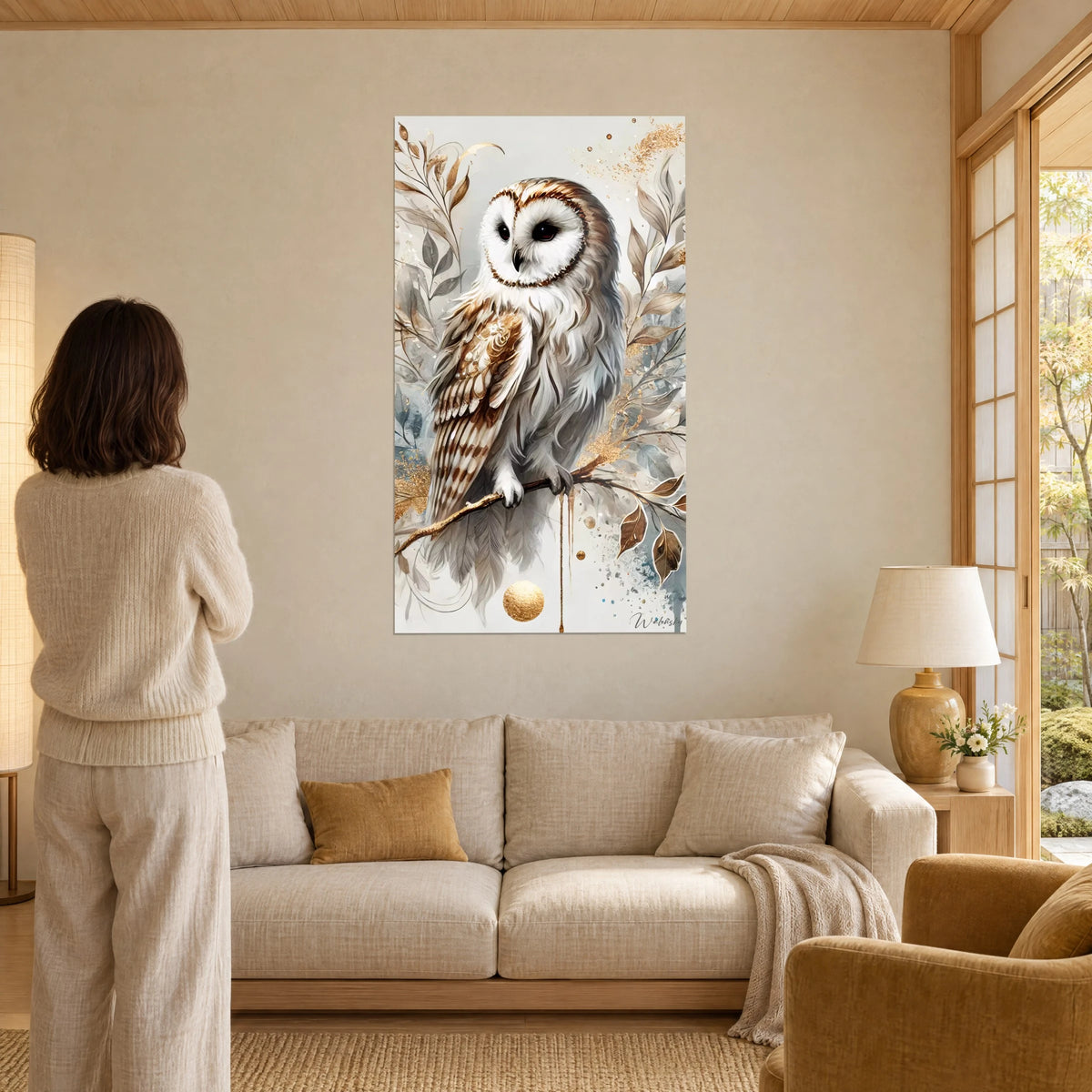 Tableau chouette effraie au plumage ivoire et cuivré, branche dorée, femme de dos, au-dessus d'un canapé dans un salon lumineux