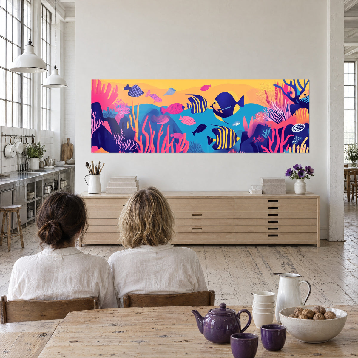 Cuadro gráfico de un arrecife de coral con peces de lunares rosas e índigo sobre cielo naranja, frente a dos personas en un loft