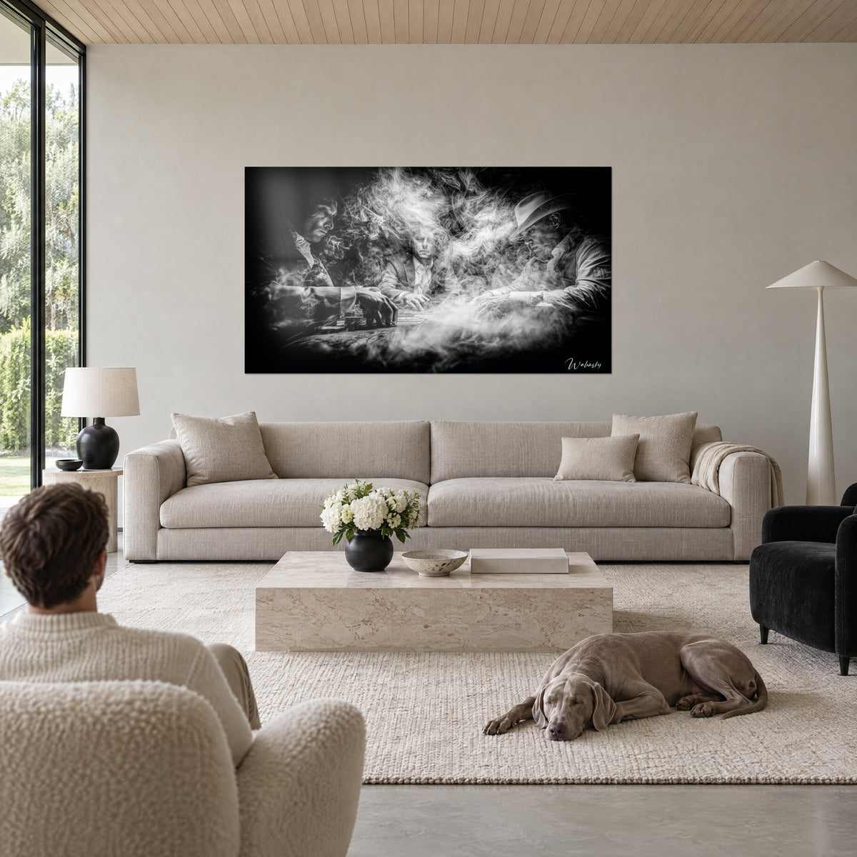 Wall art three poker players in smoke, black and white, light hat on the right, above a sofa in a bright living room