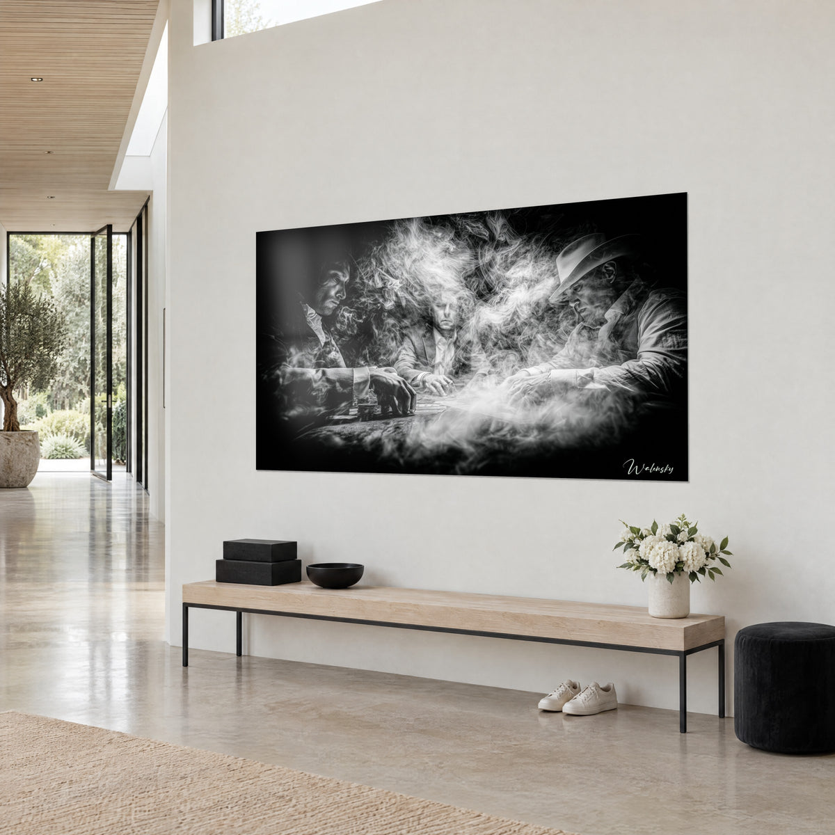 Tableau partie de cartes enfumée en noir profond et blanc cotonneux, vue de trois-quarts sur un mur crème, banc en bois clair