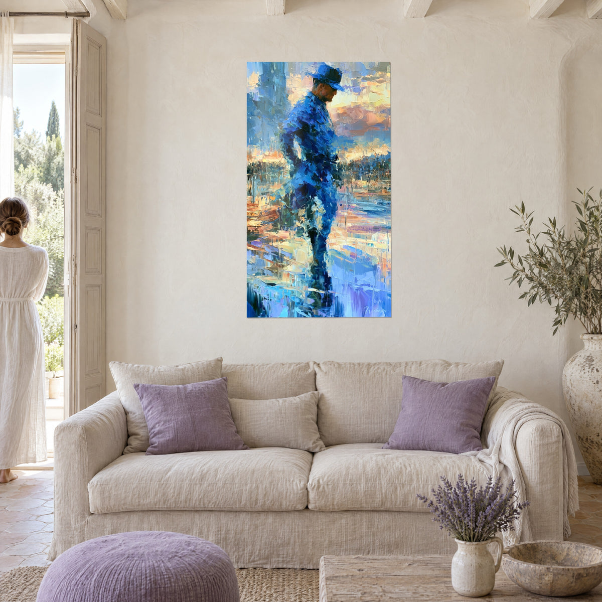 Wall art officer in cobalt blue standing facing the shore, orange and pink sky in palette knife strokes, above a sofa in a bright living room