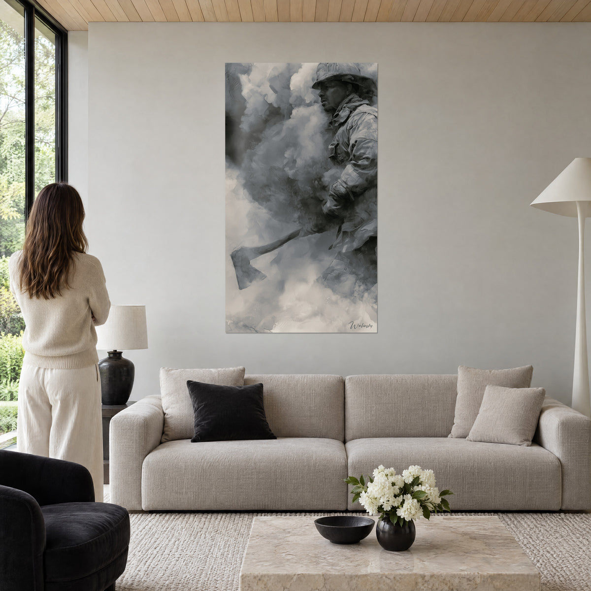 Quadro pompiere con elmetto che stringe la sua ascia nel fumo antracite e grigio, donna di spalle, sopra un divano in un soggiorno luminoso
