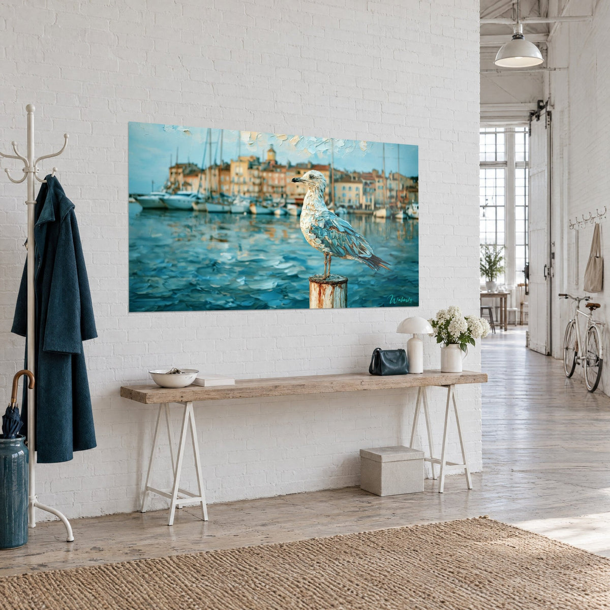 Tableau mouette en coups de couteau bleu azur et ivoire, voiliers au loin, accroché sur un mur de briques blanches d'un loft