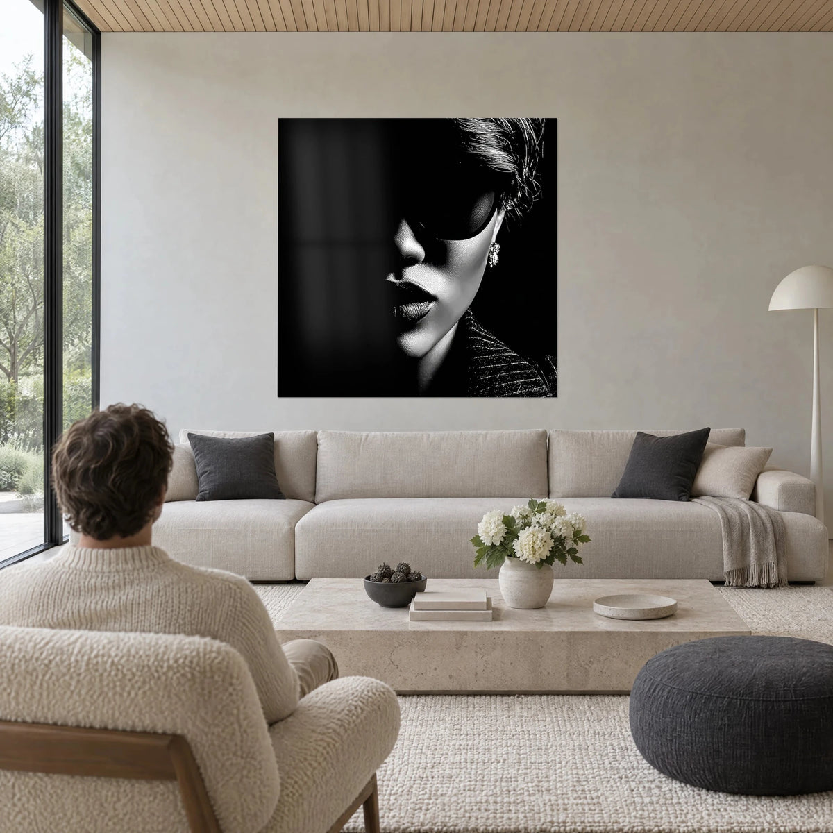Tableau visage de femme en clair-obscur, lunettes sombres, boucle d'oreille argentée, noir et blanc, au-dessus d'un canapé dans un salon lumineux