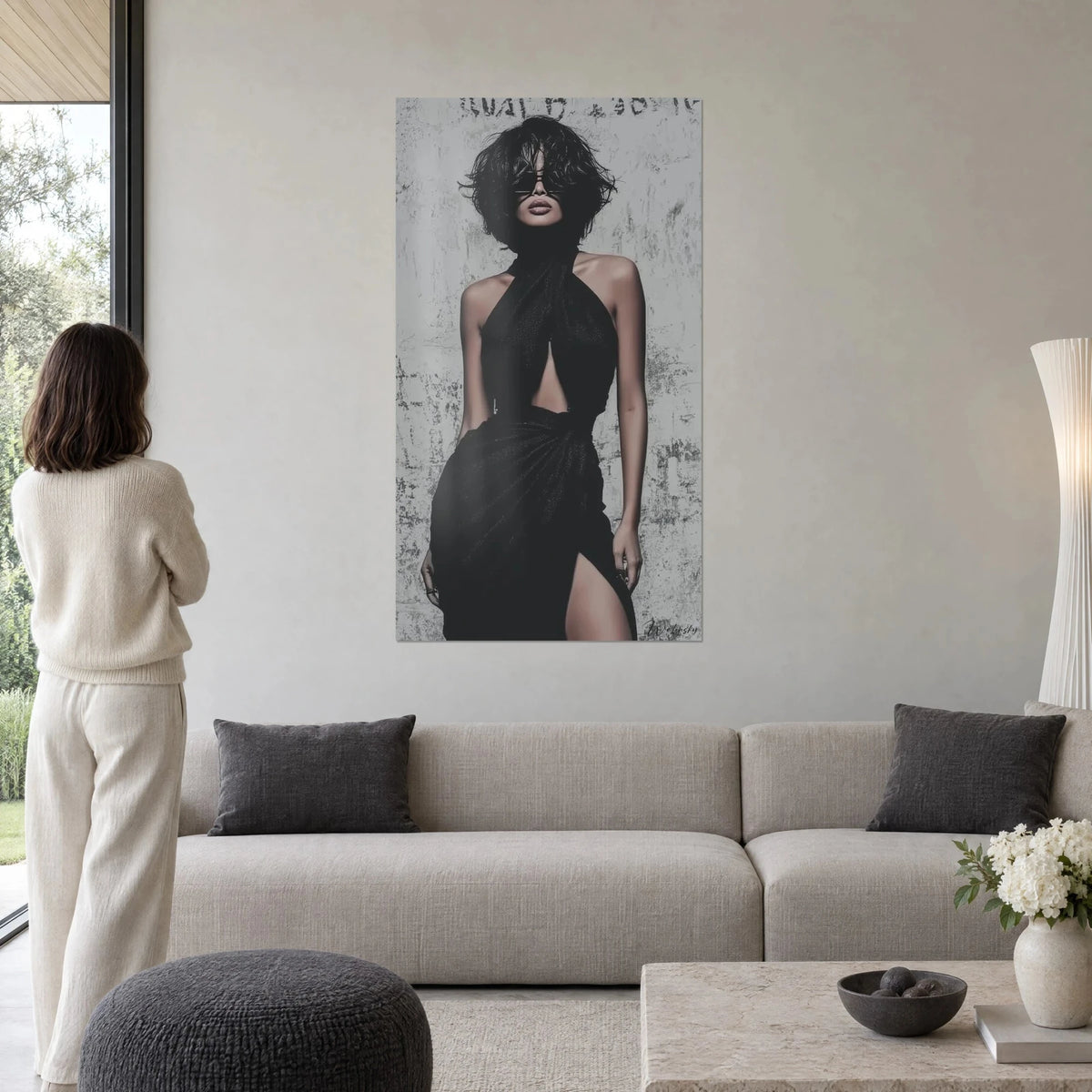 Tableau femme brune aux lunettes noires, robe dos nu noire croisée, mur gris patiné, au-dessus d'un canapé dans un salon lumineux