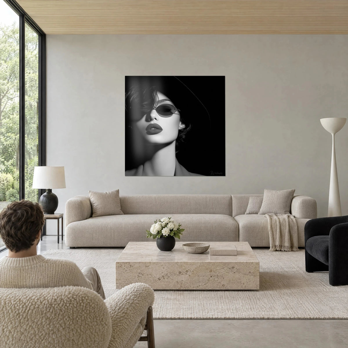 Tableau portrait de femme au chapeau noir et lunettes ovales, lèvres sombres, peau blanche, au-dessus d'un canapé dans un salon lumineux
