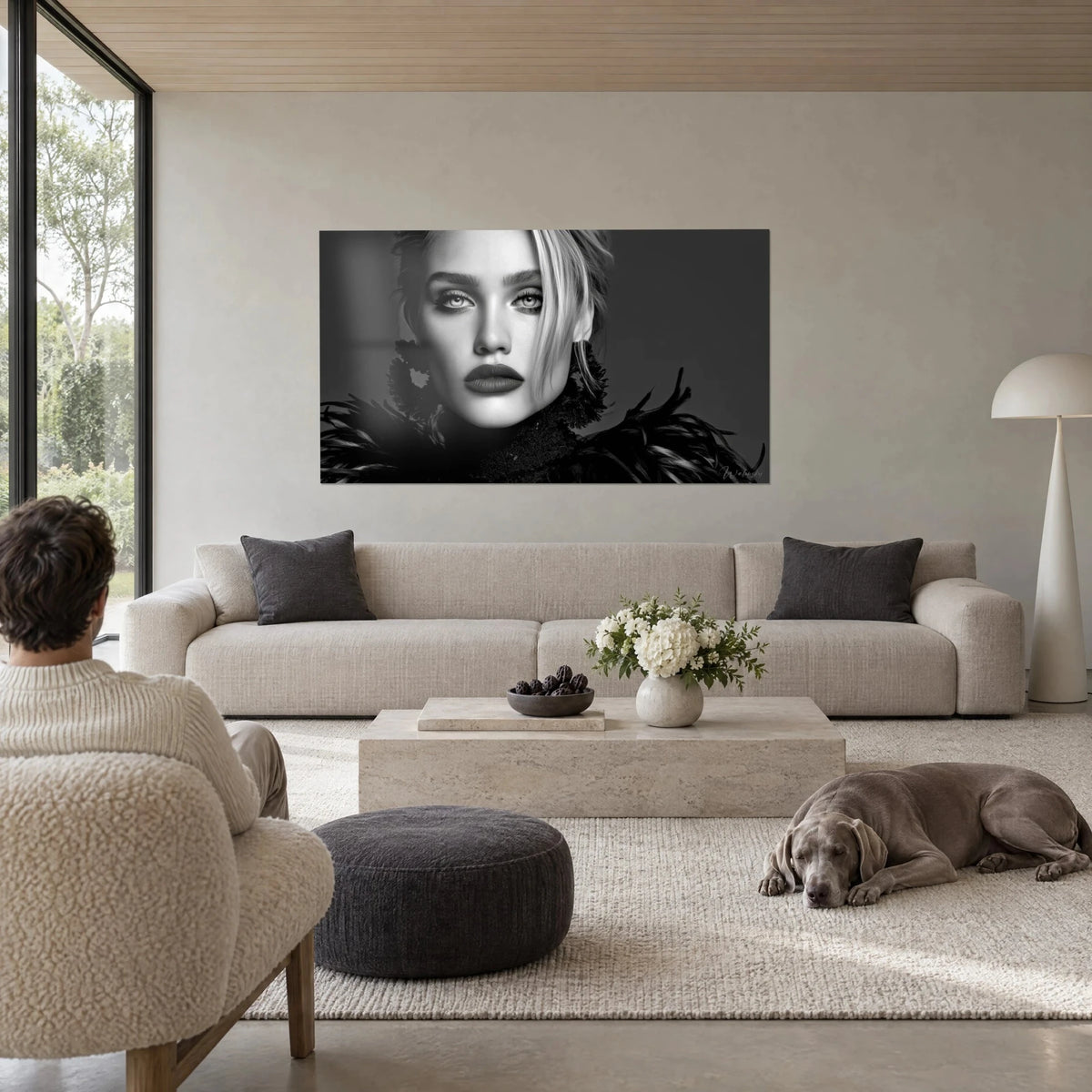 Schilderij gezicht van model met mat lippenstift, zwarte en parelgrijze veren, helder blik, boven een bank in een lichte woonkamer