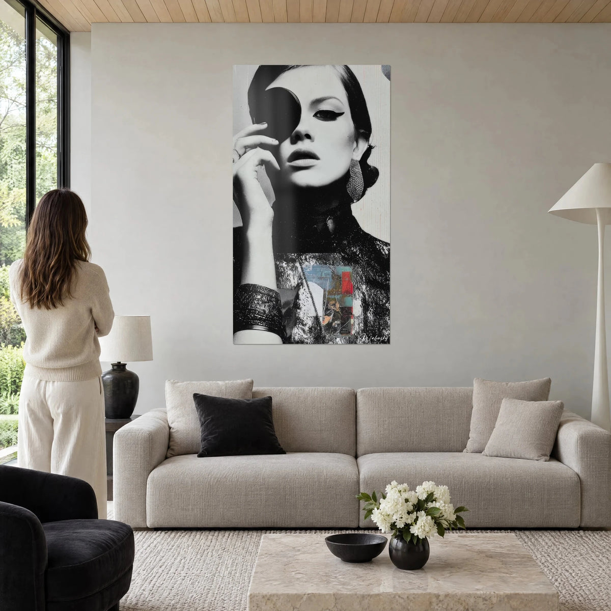 Schilderij zwart-wit portret van een vrouw die een oog bedekt met een zwarte schijf, rode en blauwe collage, boven een bank in een lichte woonkamer