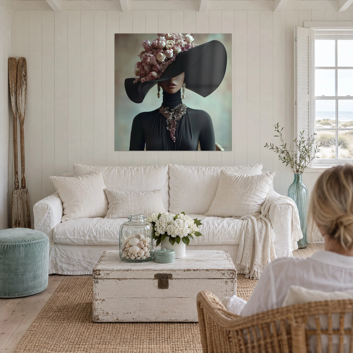 Schilderij mysterieus portret van een vrouw met zwarte hoed versierd met poederroze rozen, boven een bank in een lichte woonkamer