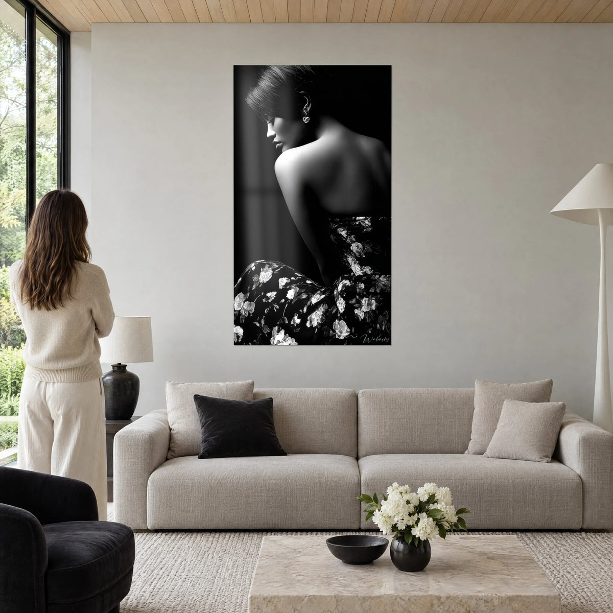 Cuadro retrato de mujer de espaldas, hombro desnudo iluminado, vestido de flores en blanco y negro, mujer de pie sobre un sofá en un salón luminoso