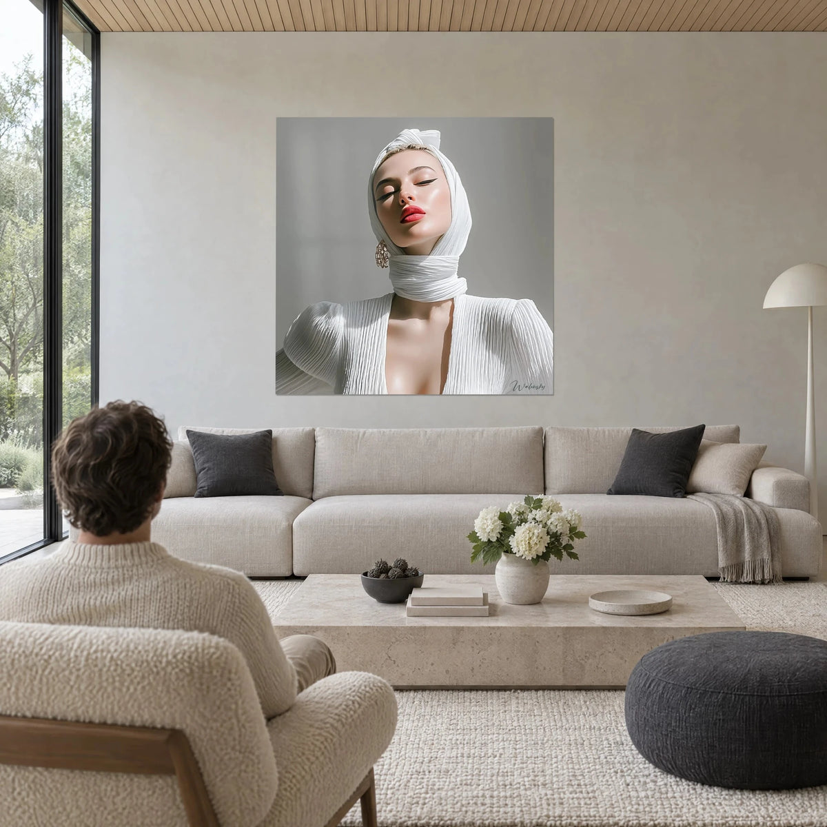 Cuadro retrato de mujer con turbante blanco plisado, labios rojos, fondo gris, un hombre de espaldas, sobre un sofá en un salón luminoso