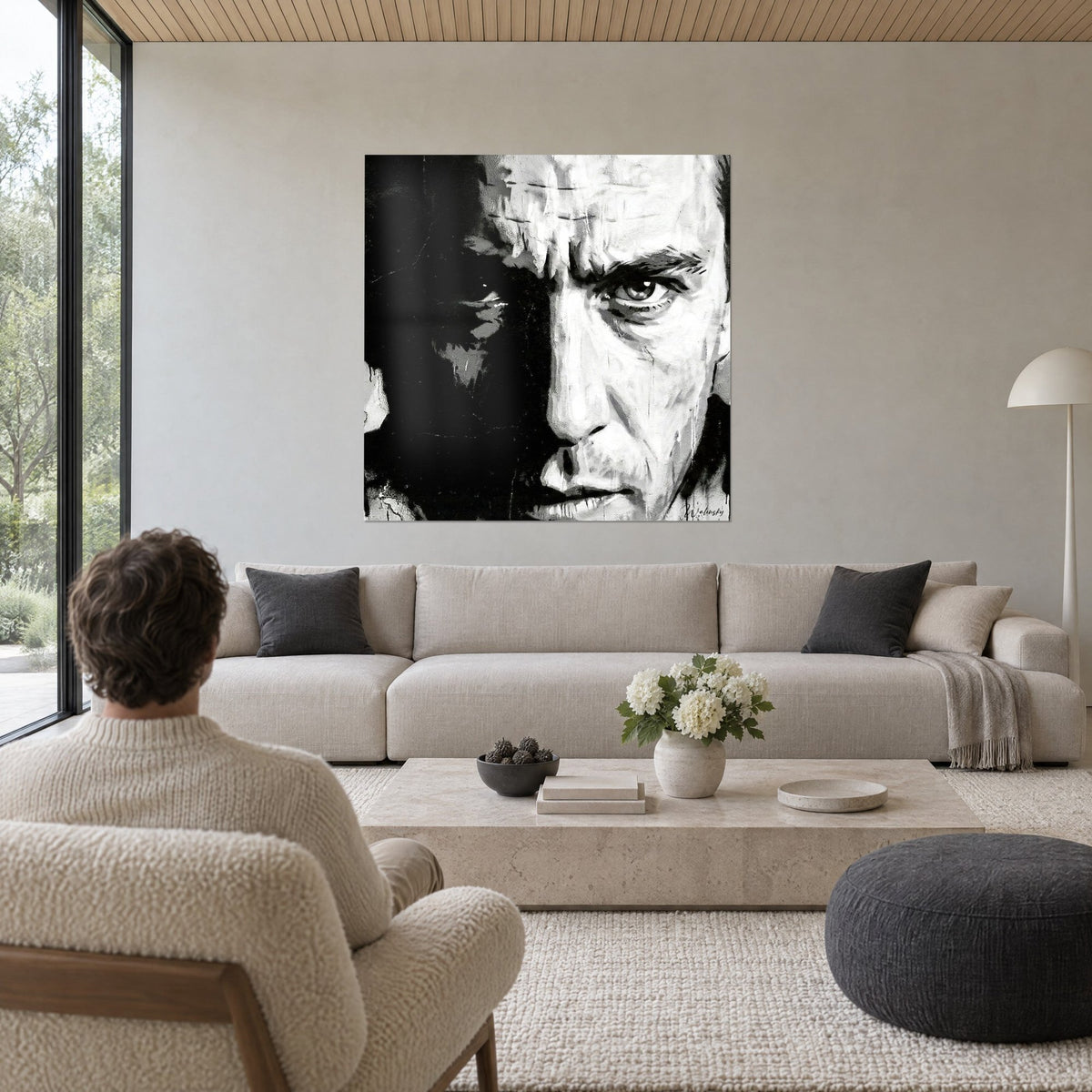 Tableau portrait masculin en noir et blanc, regard intense, coulures de peinture, deux personnes de dos au-dessus d'un canapé dans un salon lumineux