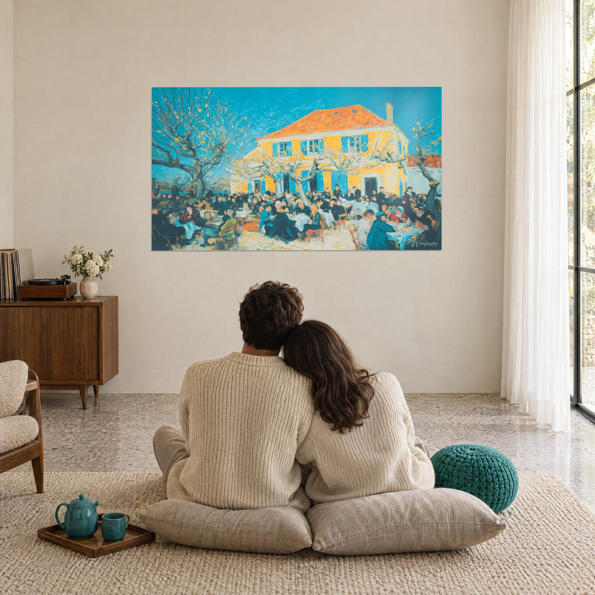 Quadro festa di paese a pittura spessa, blu oltremare e giallo vivo, ammirato da una coppia seduta di spalle su cuscini beige