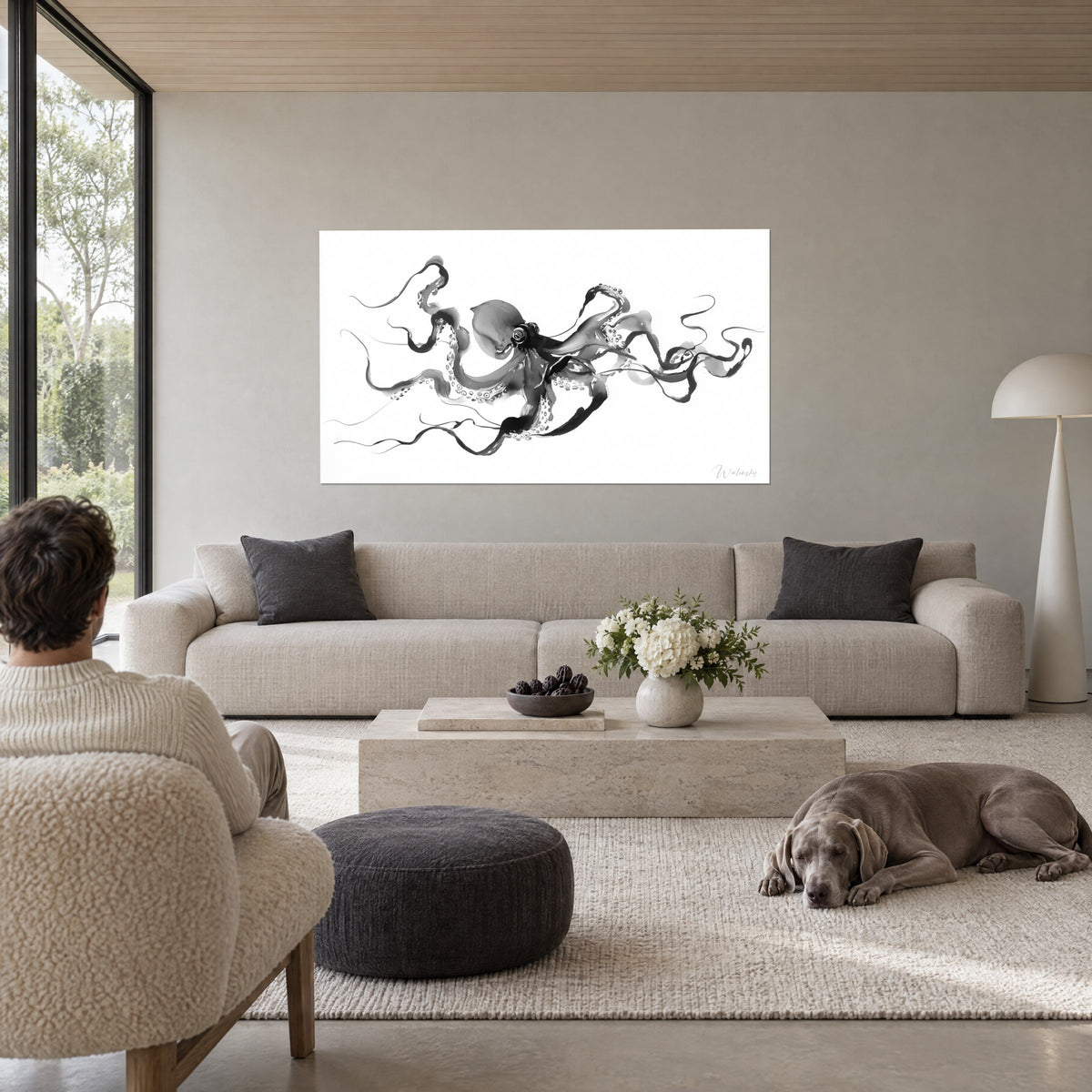Cuadro pulpo en tinta negra y gris, tentáculos esbeltos sobre fondo blanco, hombre de espaldas, encima de un sofá en un salón luminoso