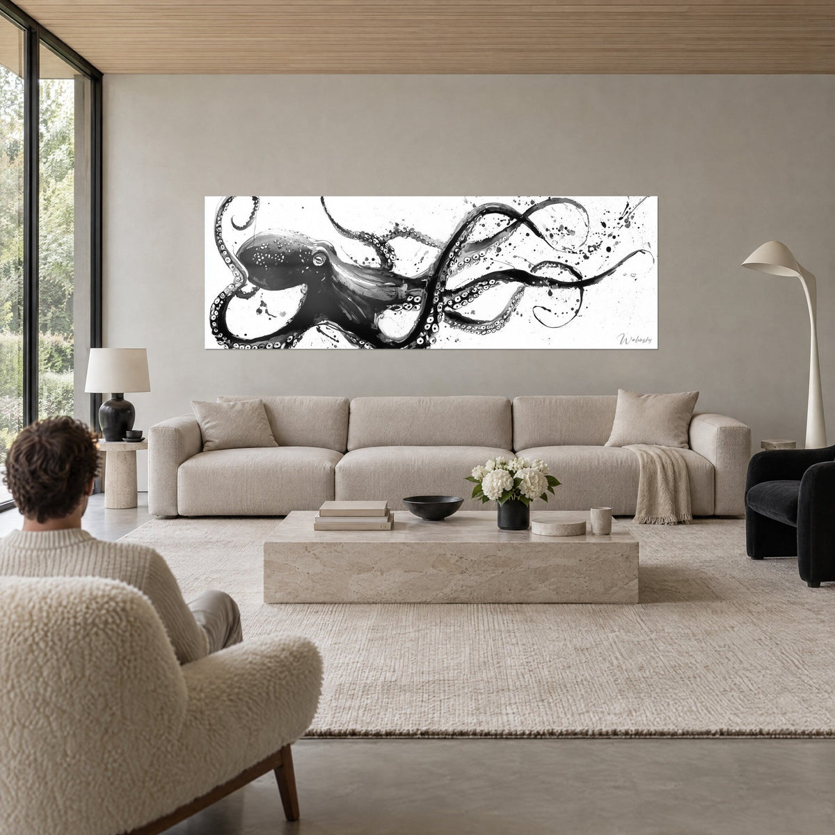 Wall art black ink octopus with coiled tentacles, white background, grey wall, above a sofa in a bright living room