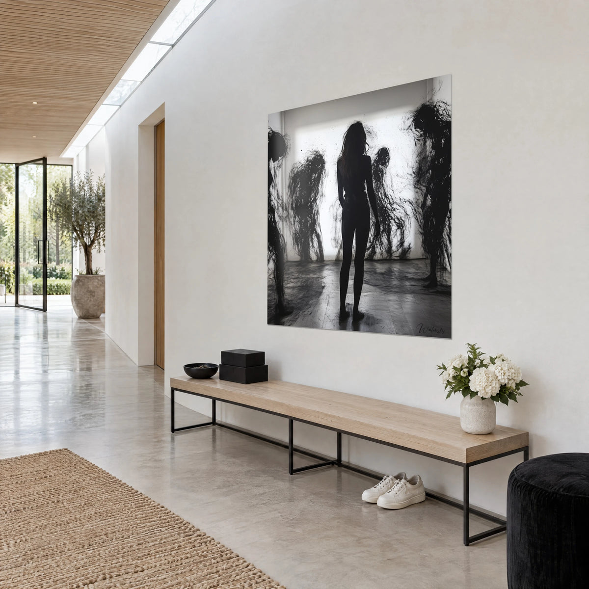 Cuadro mujer de pie en sombra negra, salpicaduras de tinta y formas fantasmales desordenadas sobre blanco luminoso, pared crema junto a un banco de madera