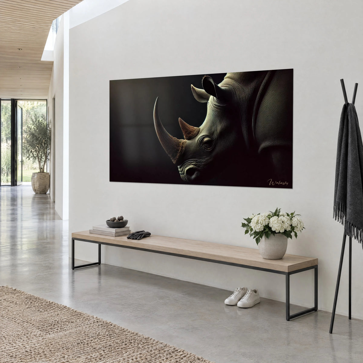 Quadro del muso di un pachiderma corazzato, corno ambrato e occhio socchiuso nell'ombra, su una parete bianca con panca in legno