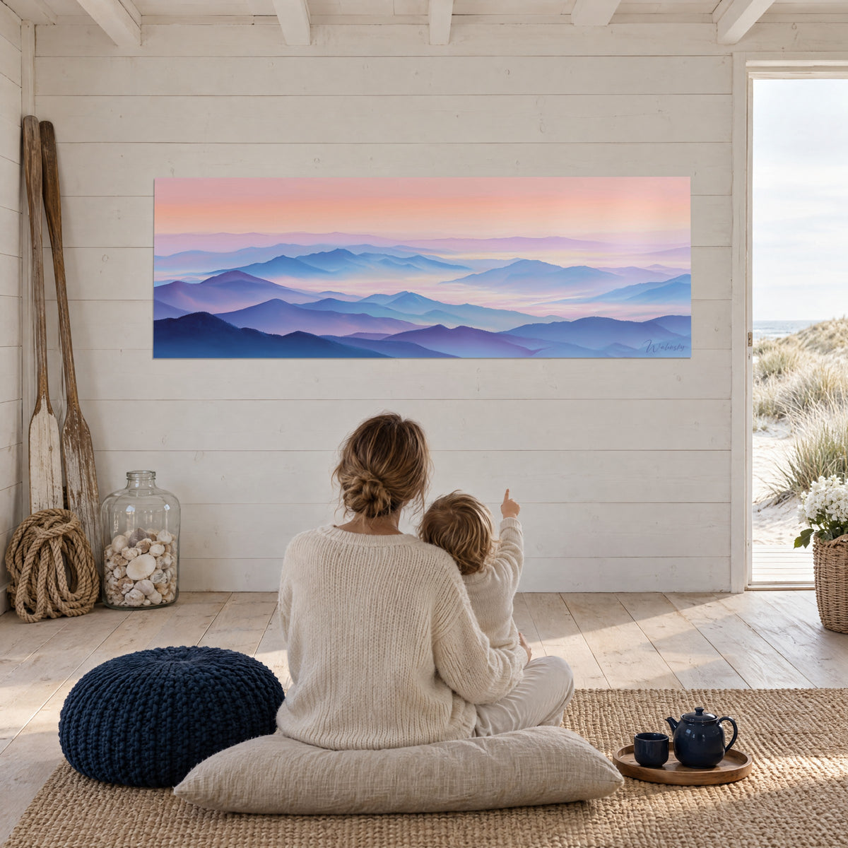 Wall art of dawn over the Pyrenees in cobalt blue and coral pink, mother and child seen from behind sitting on a cushion, beach house
