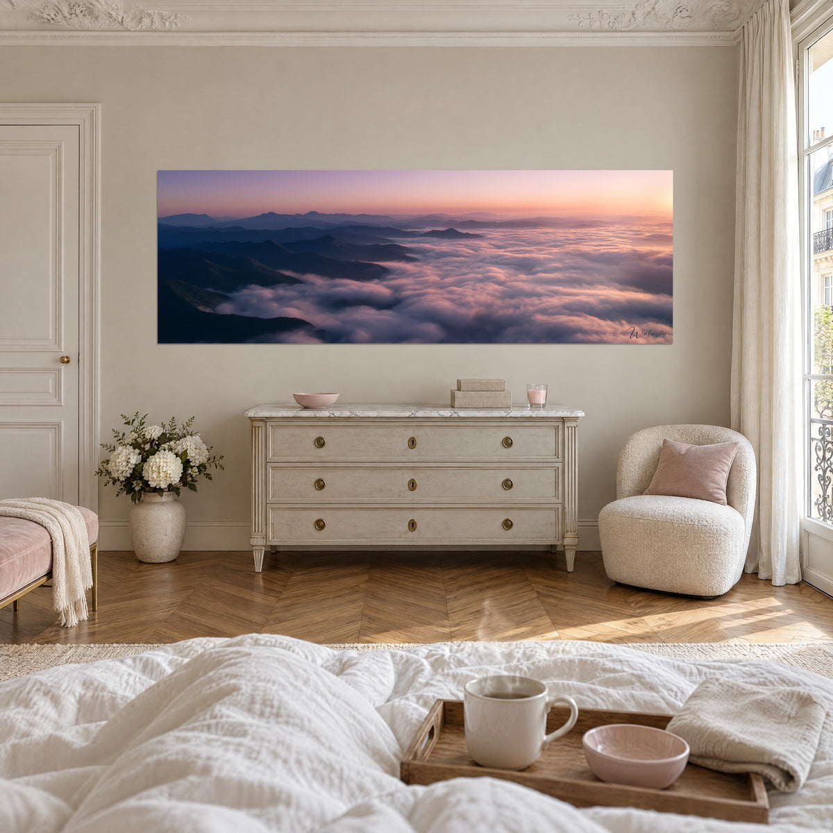 Schilderij blauwige bergkammen boven een wolkendek in lichtroze en perzik, panoramische lijst, boven een bed in een heldere slaapkamer