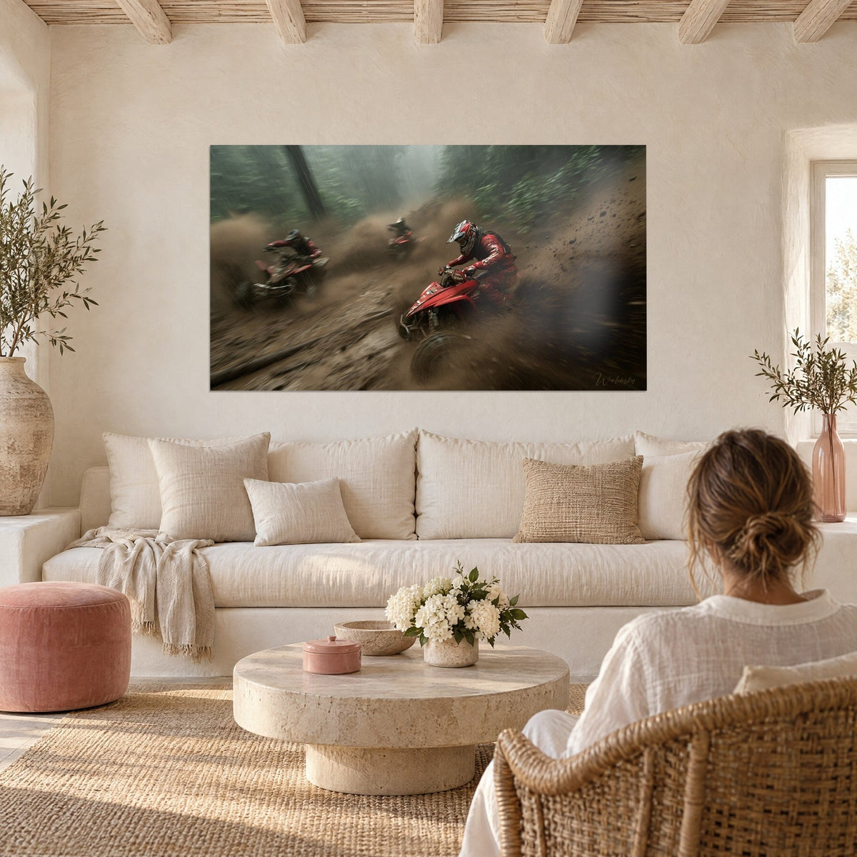 Wall art trio of quad bikes splashing through mud in the rain, rider in red suit and white helmet, above a sofa in a bright living room