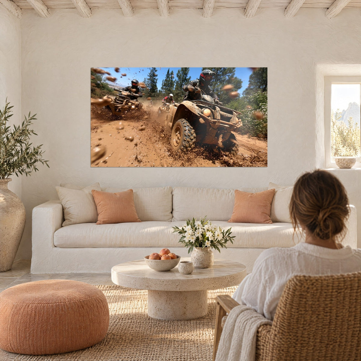 Wall art of a brown quad bike tearing through mud, ochre splashes and green pines, above a sofa in a bright living room