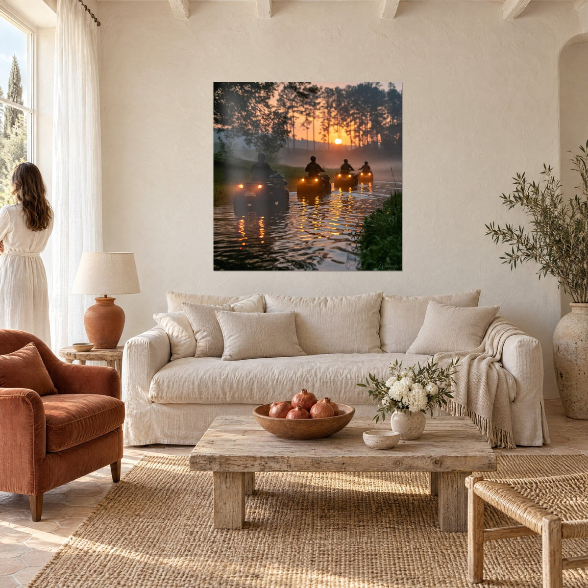 Wall art quads riding in line through a misty river, orange sun and pine forest, above a sofa in a bright living room
