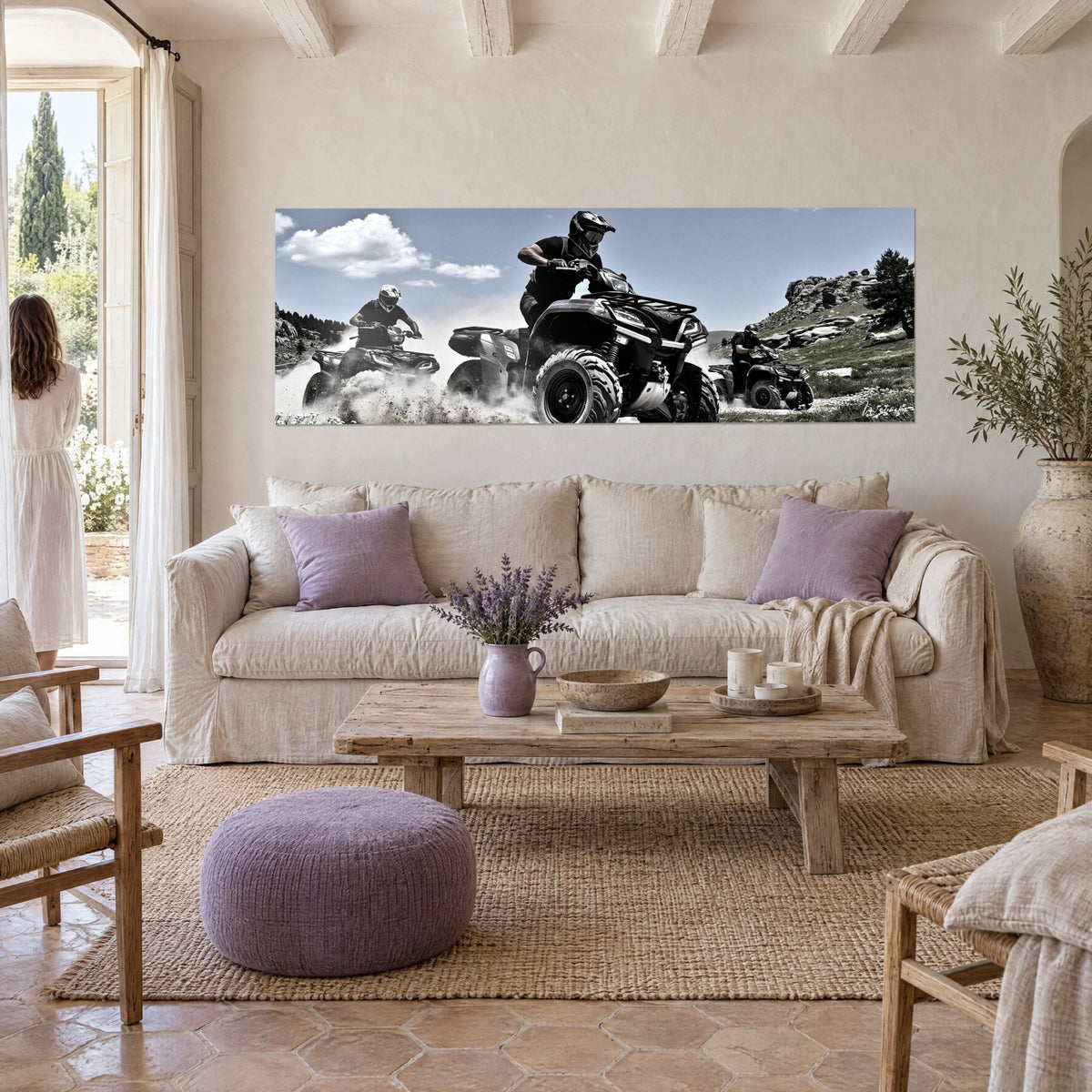 Tableau trois quads noirs lancés sur un chemin poussiéreux, ciel bleu et nuages blancs, au-dessus d'un canapé dans un salon lumineux