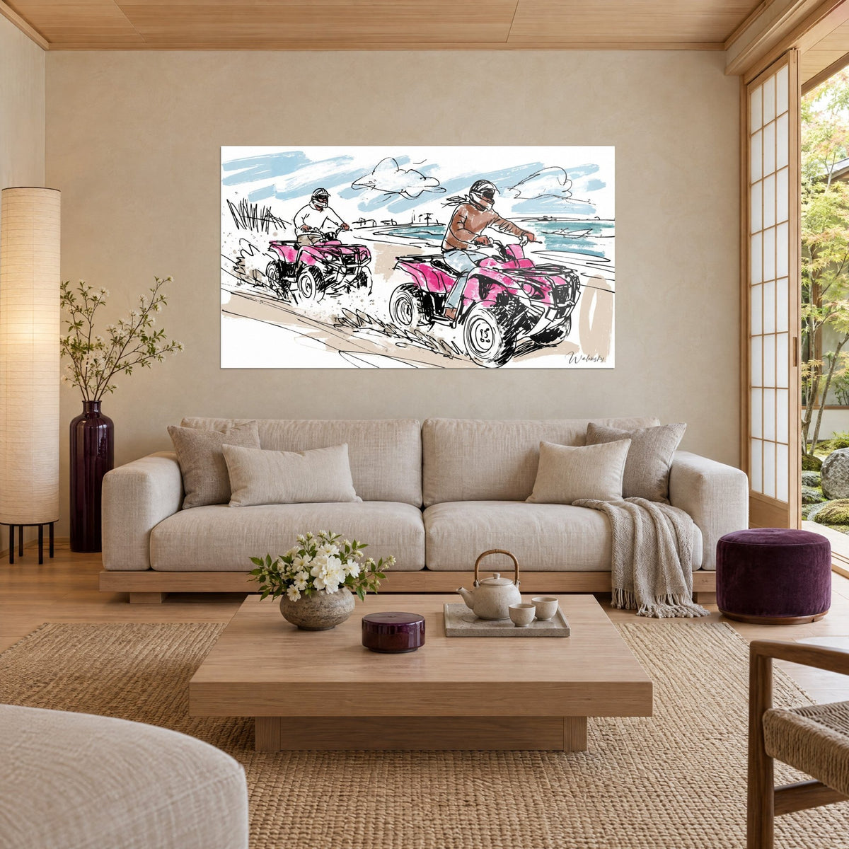 Wall art of pink quad bikes launching across the sand, helmeted riders, pale blue sky and turquoise sea, above a sofa in a bright living room