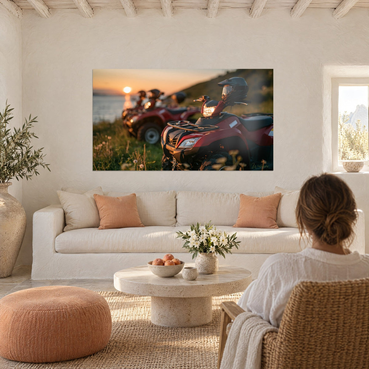 Wall art of burgundy quad bikes lined up facing the sea, orange sun on the water, black helmet, above a sofa in a bright living room