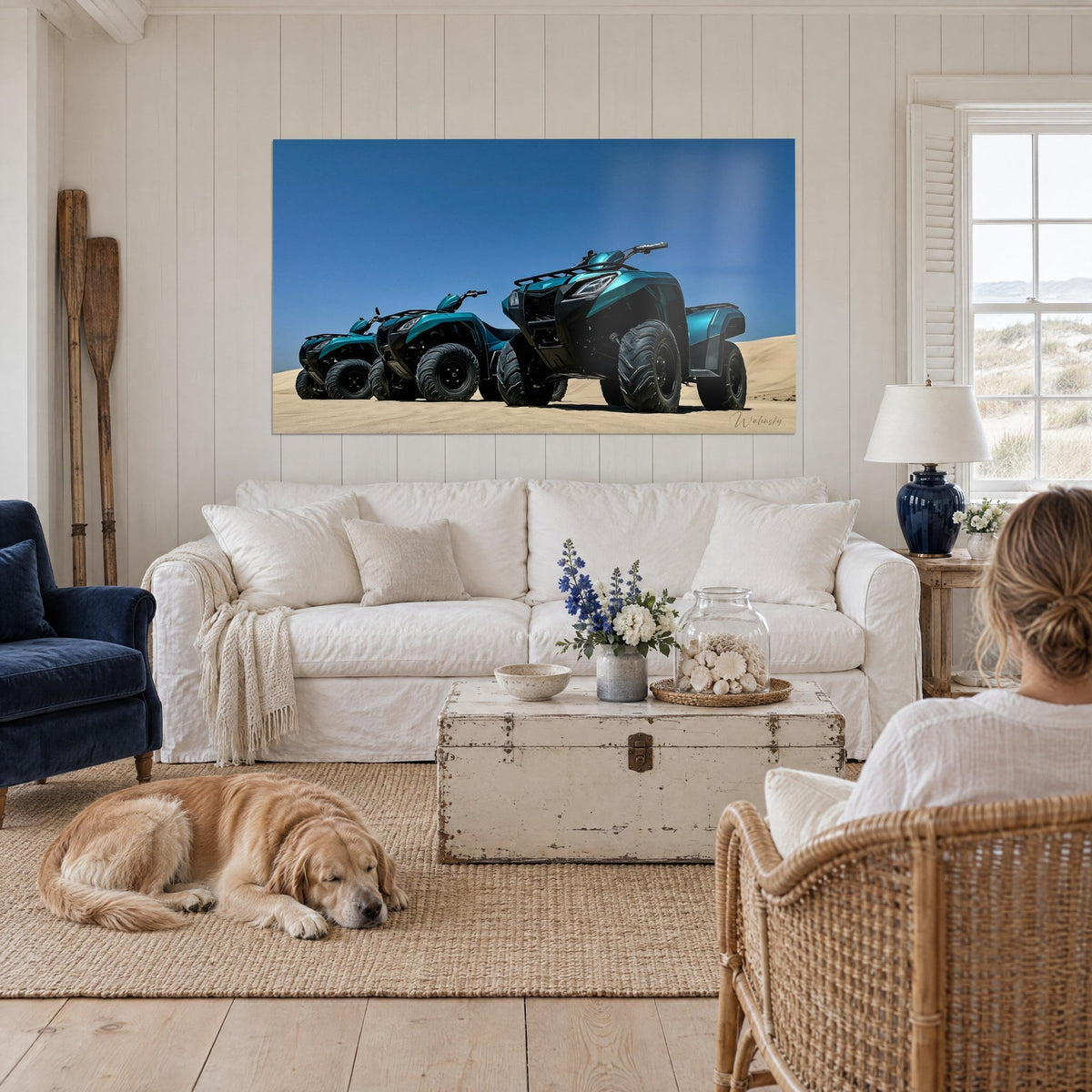 Cuadro quads turquesa alineados sobre una duna beige, cielo azul intenso, retriever tumbado, encima de un sofá en un salón luminoso