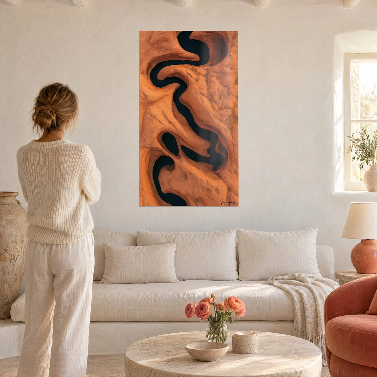 Wall art canyon of carved orange sandstone, winding black river, above a sofa in a bright living room