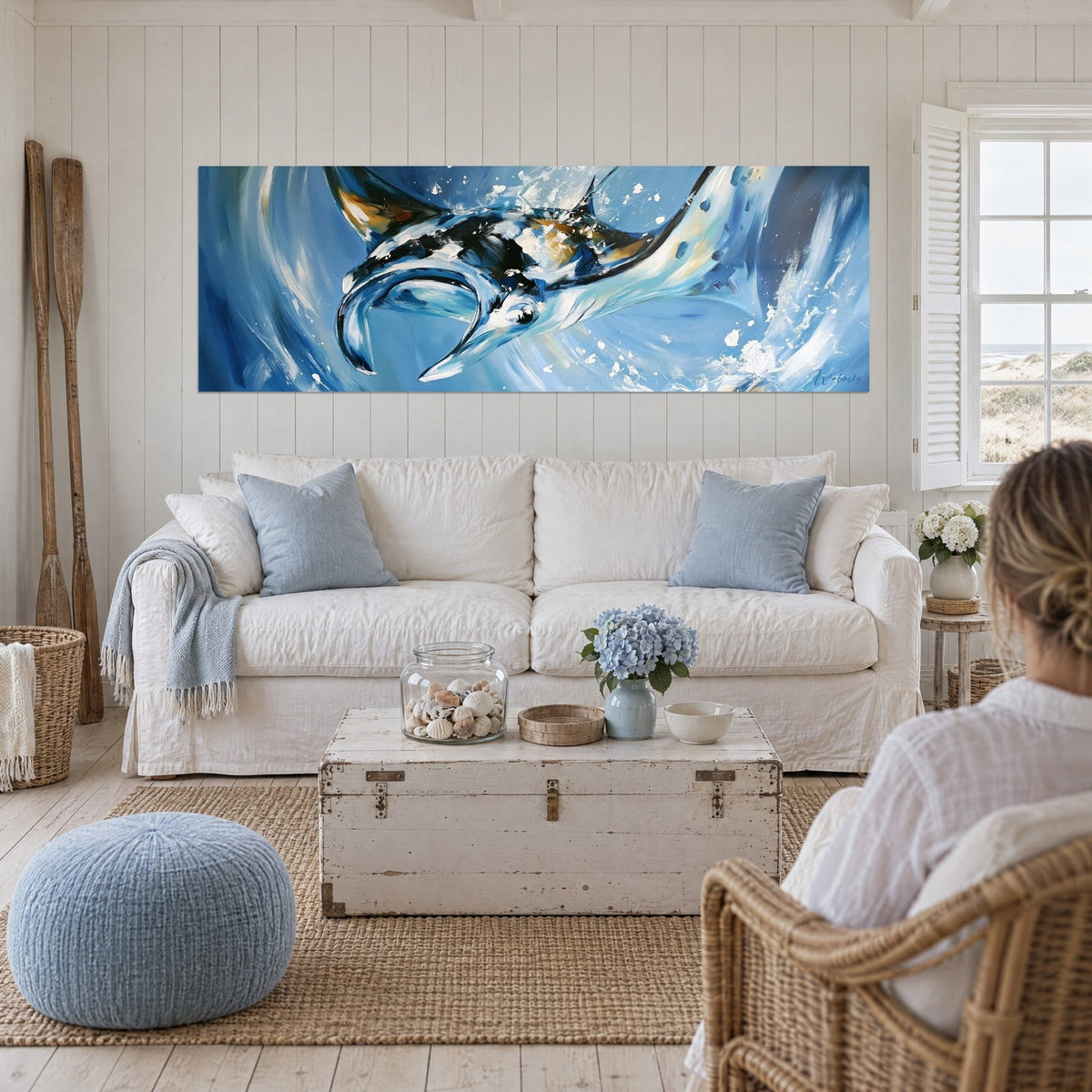 Tableau raie manta bleue et noire aux éclaboussures blanches, deux personnes de dos, au-dessus d'un canapé dans un salon lumineux