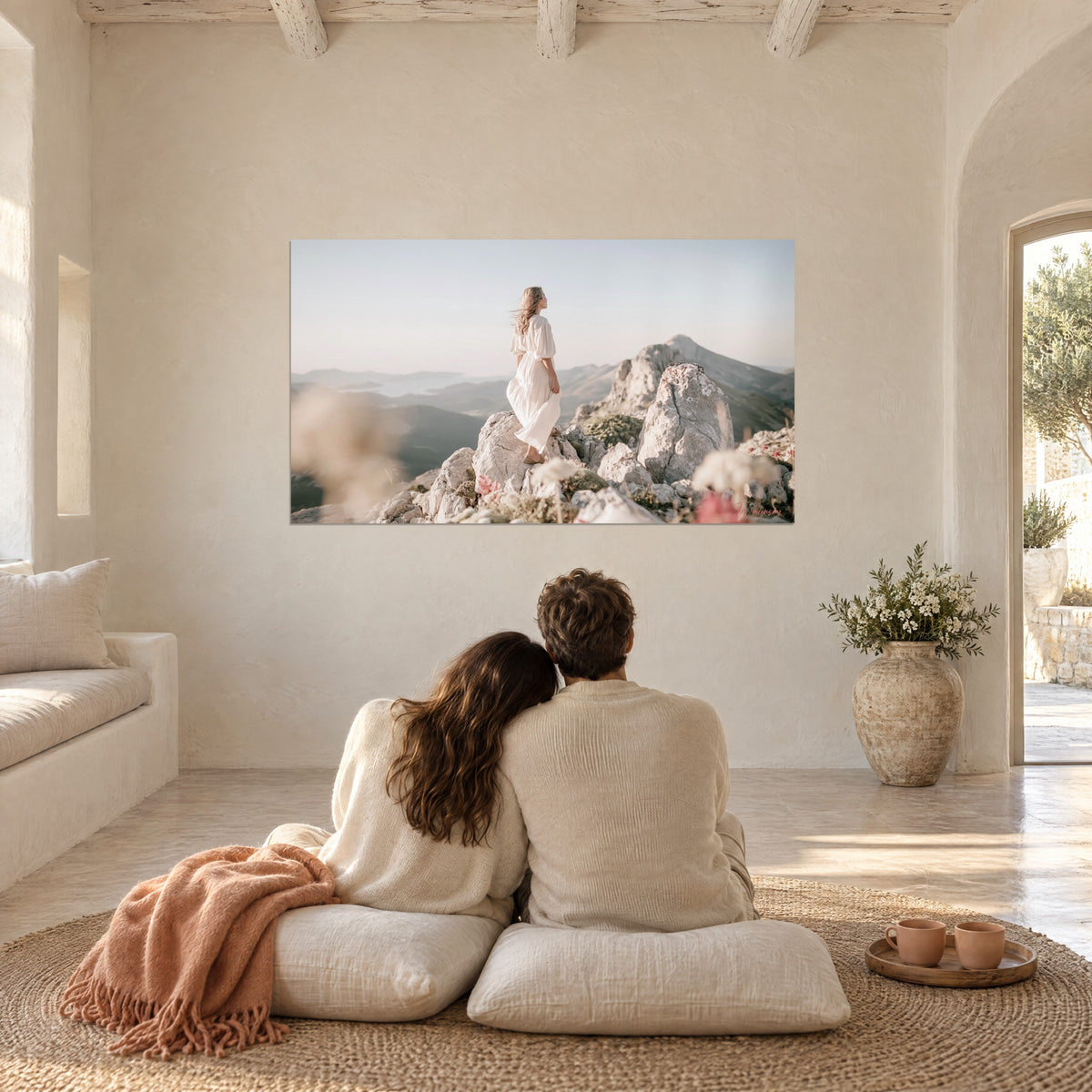 Wall art mountain peak and woman in a linen dress, grey stones, pinkish sky and wild flowers, simple Provençal living room in sand tones