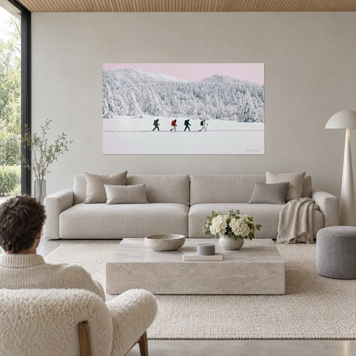 Tableau quatre marcheurs en file sur la neige, sapins givrés et ciel rose pâle, au-dessus d'un canapé dans un salon lumineux