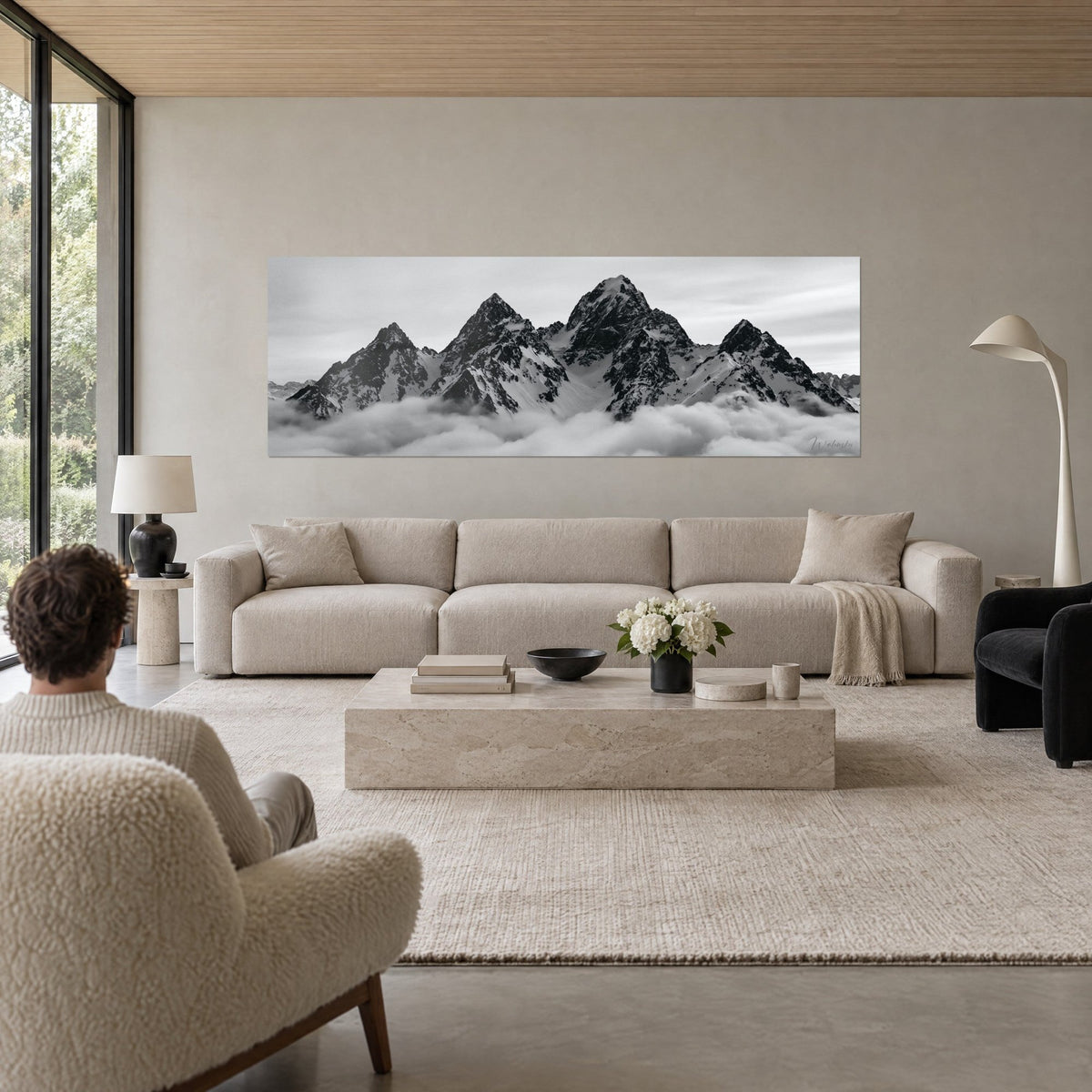 Gemälde schneebedeckte Gipfel in Schwarzweiß, von Wolken durchbrochen, dunkler Fels und weißer Schnee, über einem Sofa in einem hellen Wohnzimmer