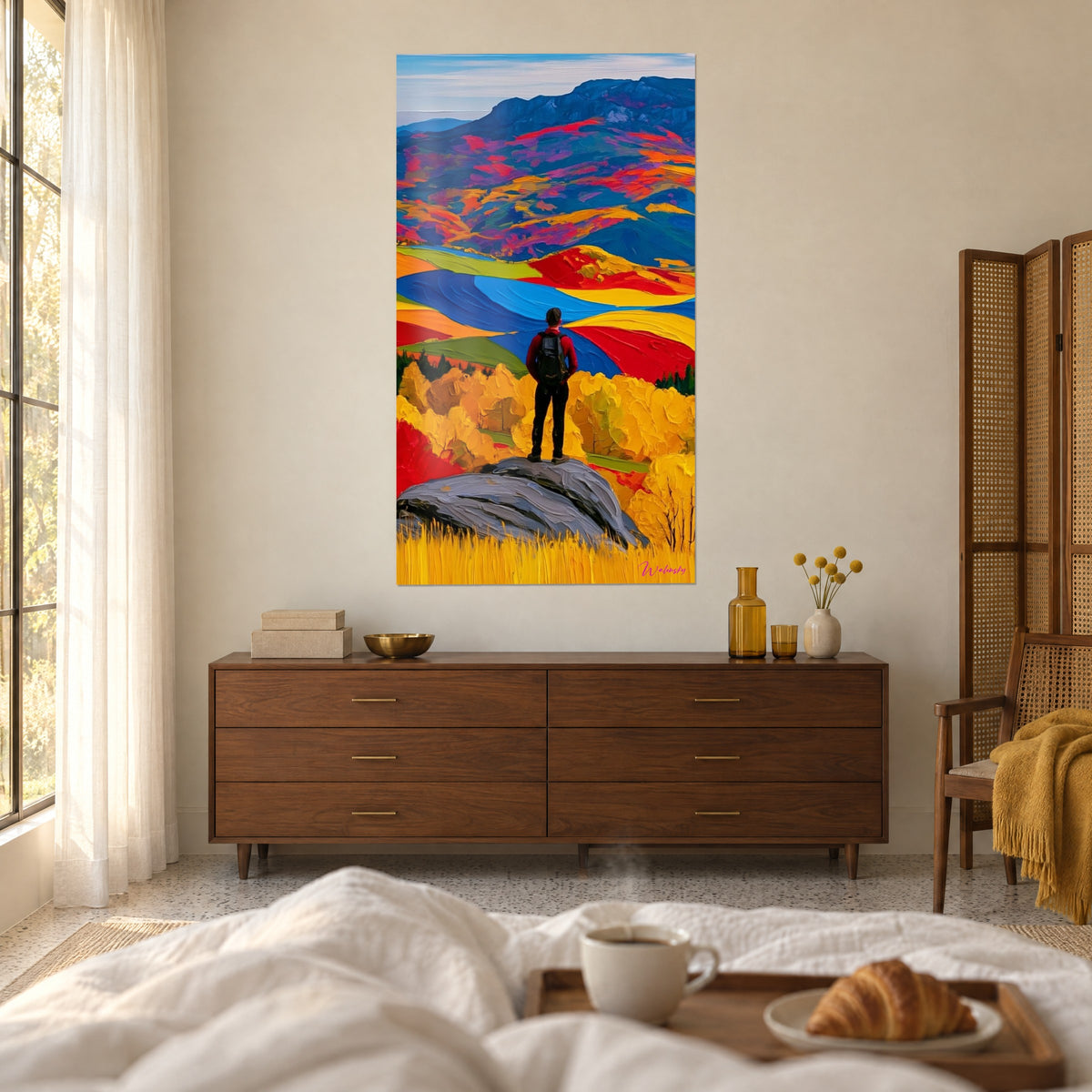 Schilderij wandelaar van achteren op een grijze rots met uitzicht op goudgele en rode bossen, boven een bed in een lichte slaapkamer