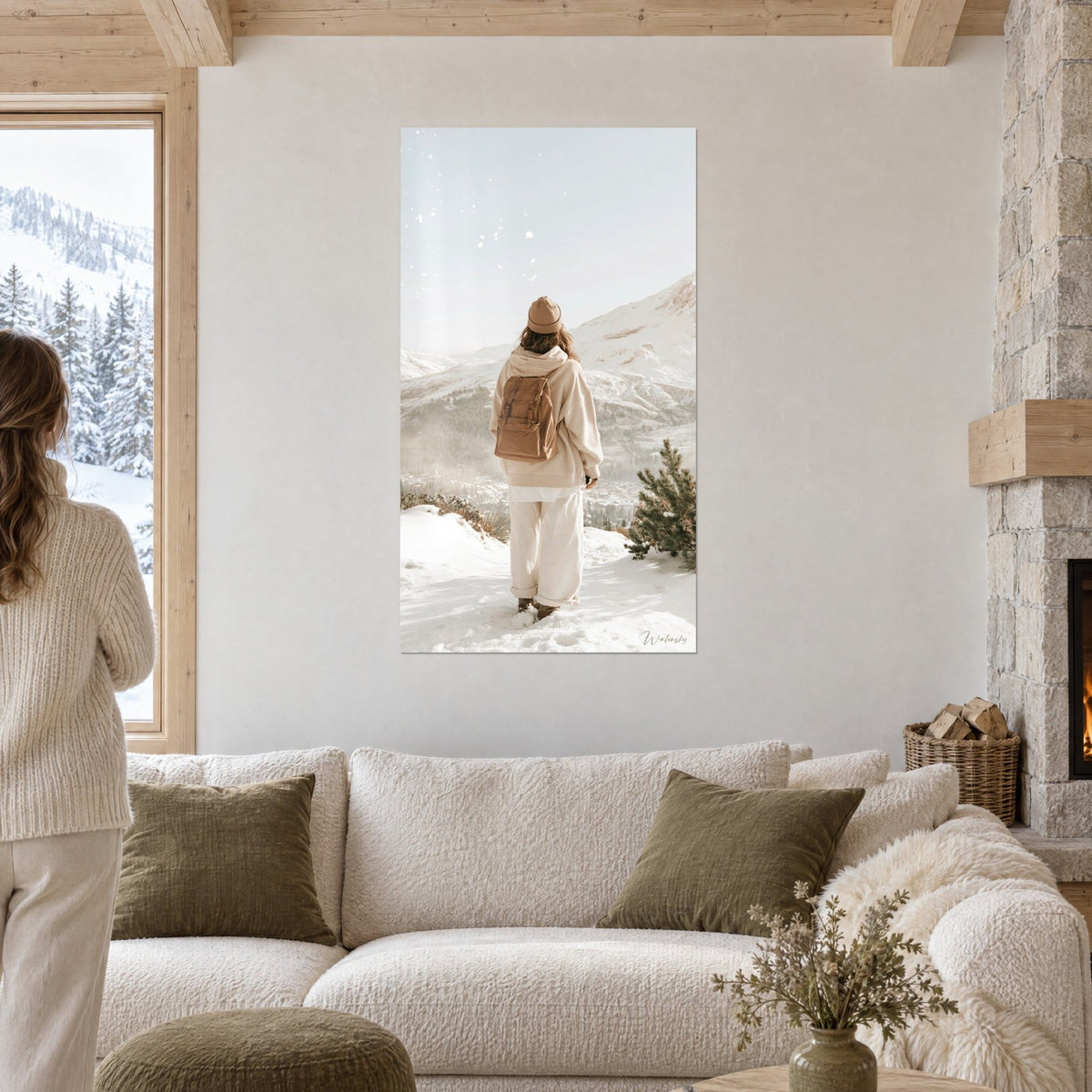 Tableau randonneuse de dos en pull crème, sac brun et bonnet camel face aux sommets neigeux, au-dessus d'un canapé dans un salon lumineux