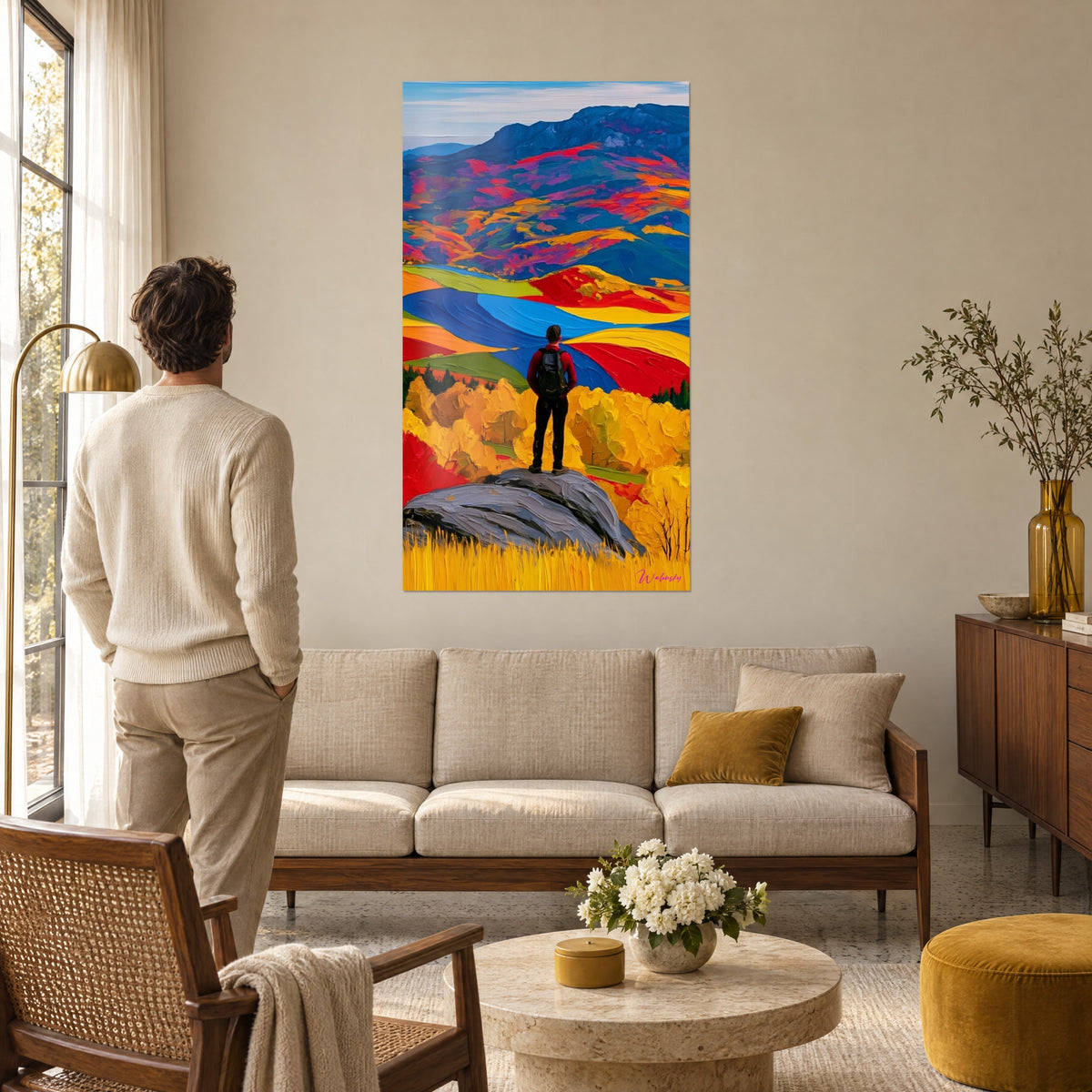 Schilderij wandelaar in rode jas op een grijze rots, rode en blauwe heuvels, boven een bank in een lichte woonkamer