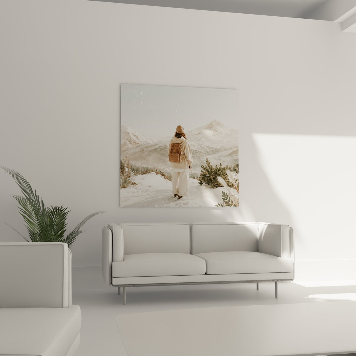 Silhouette vêtue de beige contemplant des montagnes blanches, accrochée au-dessus d'un canapé dans un salon lumineux