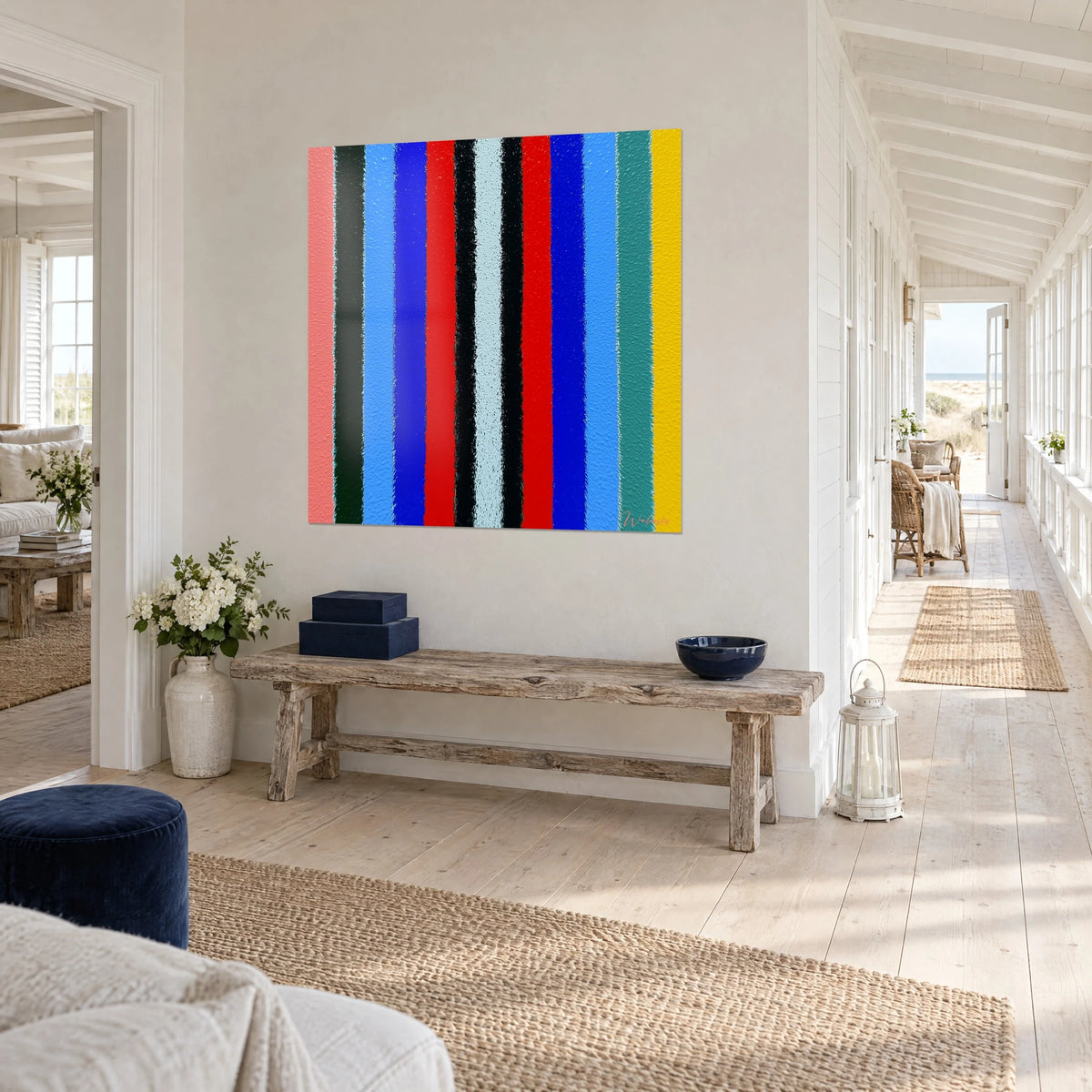 Obraz z kolorowymi pasami op art w łososiowym różu, złotym żółtym i jodłowej zieleni, na białej ścianie na końcu słonecznego korytarza