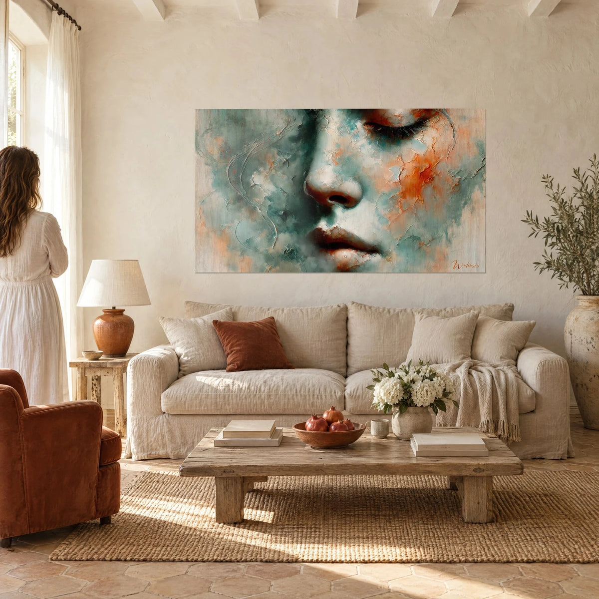 Wall art painted portrait with closed eyelids in turquoise and rust orange, woman seen from behind in the foreground, hanging above a sofa in a bright living room