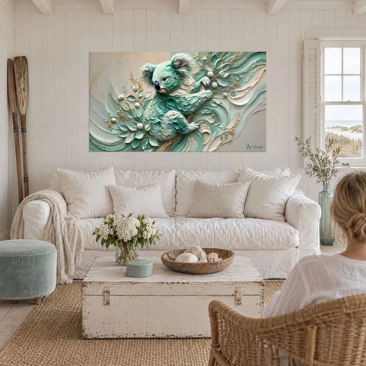 Wall art of a mint green koala in raised texture, clinging to golden branches, in cream and gold, above a sofa in a bright living room