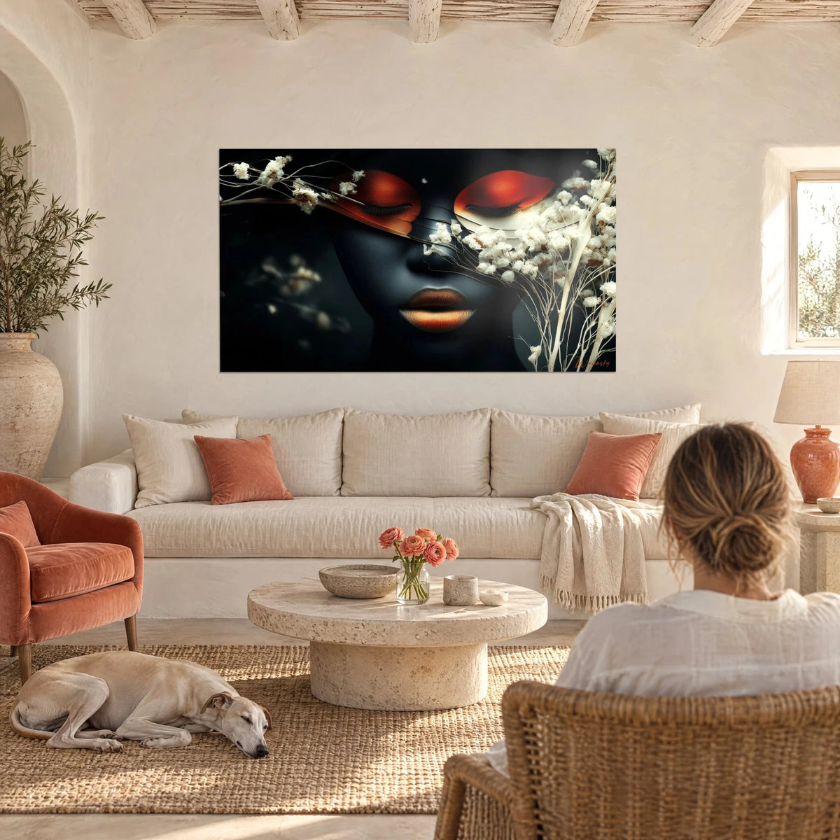 Gemälde Gesicht in Schwarz mit geschlossenen orangefarbenen Lidern, weiße getrocknete Blüten, kupferfarbene Lippen, über einem Sofa in einem hellen Wohnzimmer