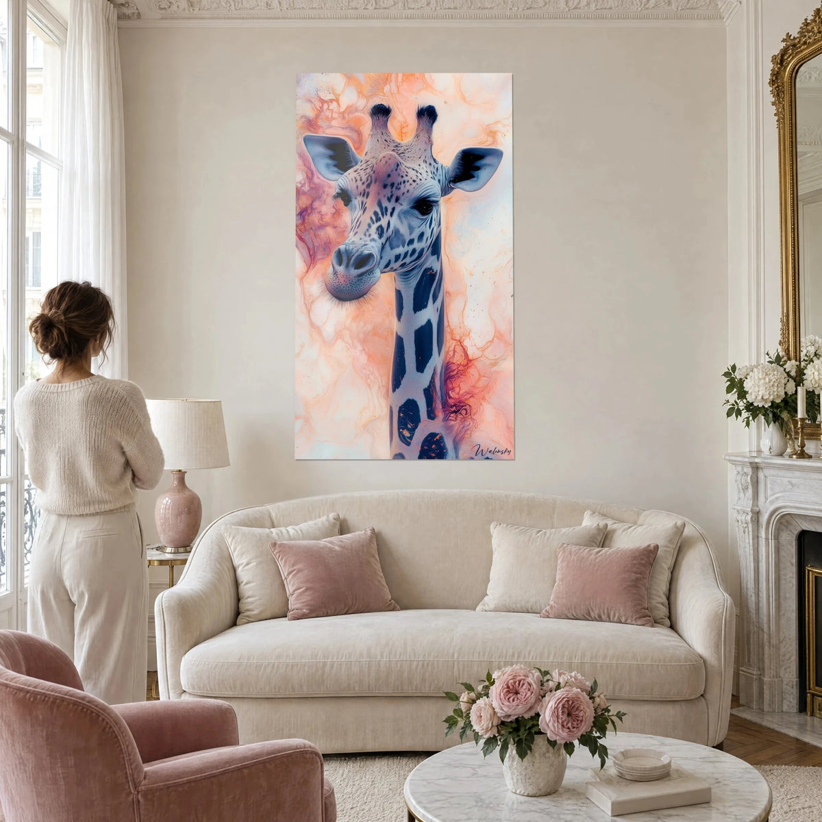 Quadro di giraffa dal collo lungo punteggiato di blu notte, sfondo marmorizzato corallo e rosa, una donna di spalle sopra un divano in un soggiorno luminoso