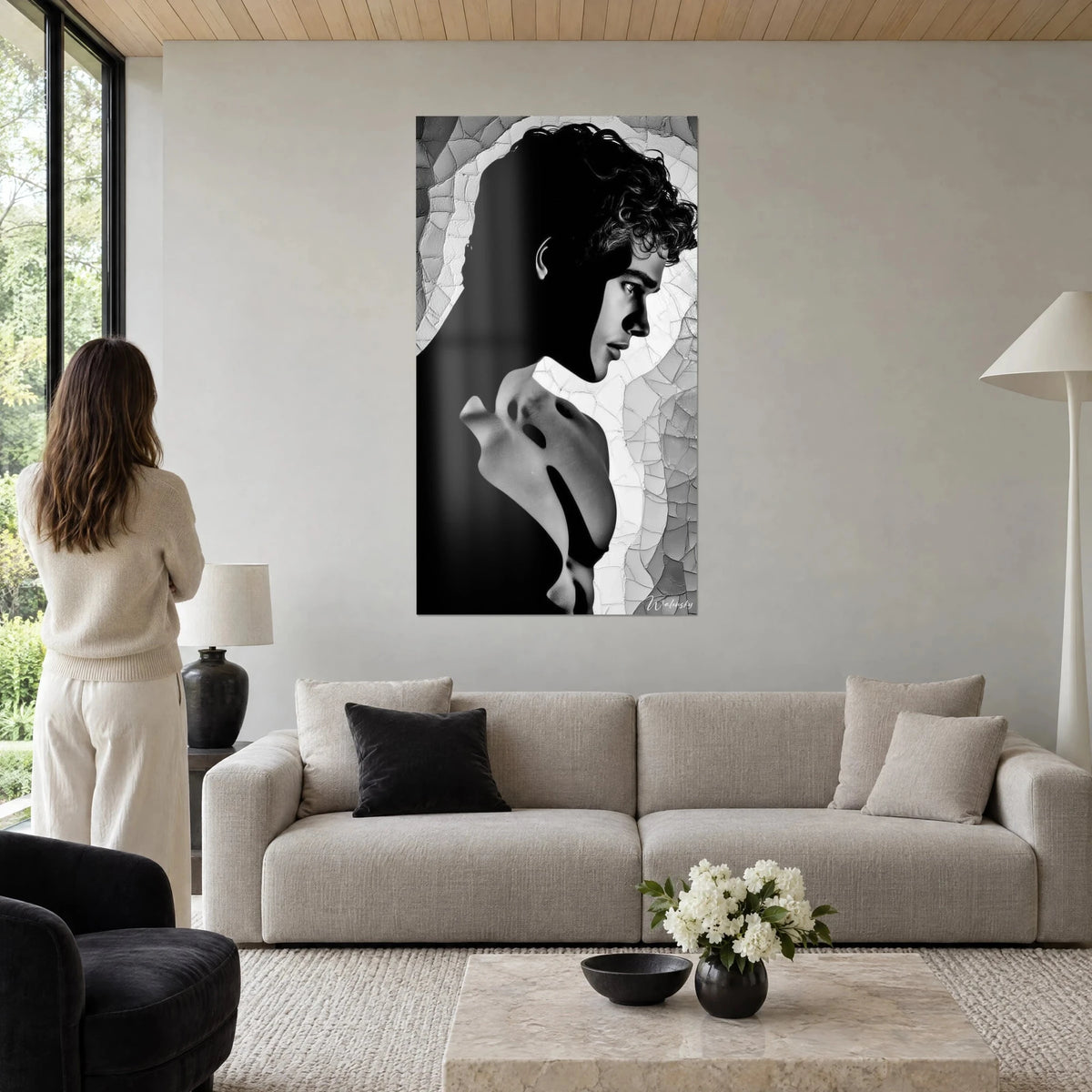 Tableau profil d'un jeune homme aux boucles noires, épaule nue grise sur mosaïque craquelée, femme de dos, au-dessus d'un canapé dans un salon lumineux